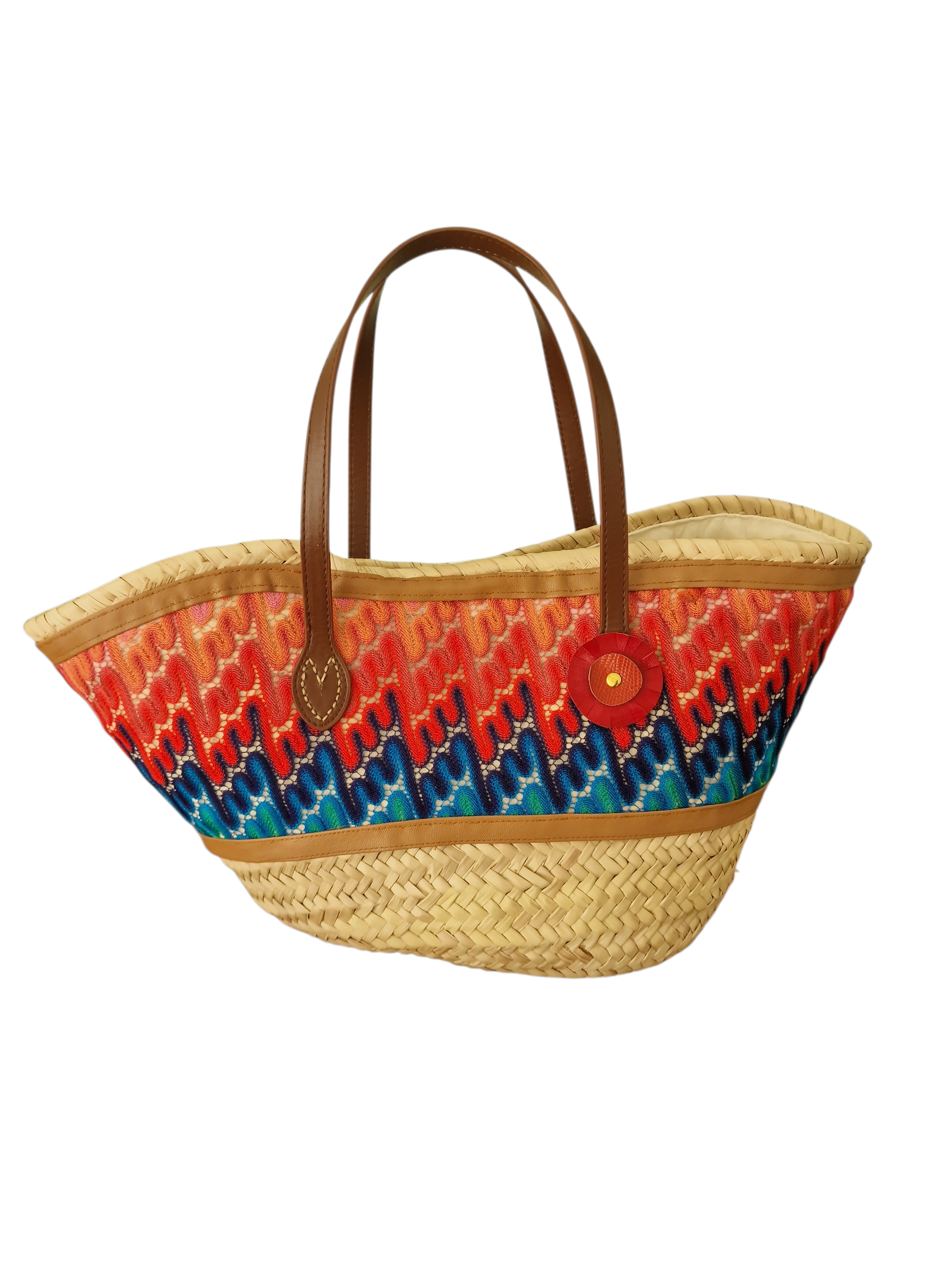 Vista frontale della borsa Magma: struttura in paglia intrecciata, manici in pelle e inserto in tessuto multicolor a trama dinamica.