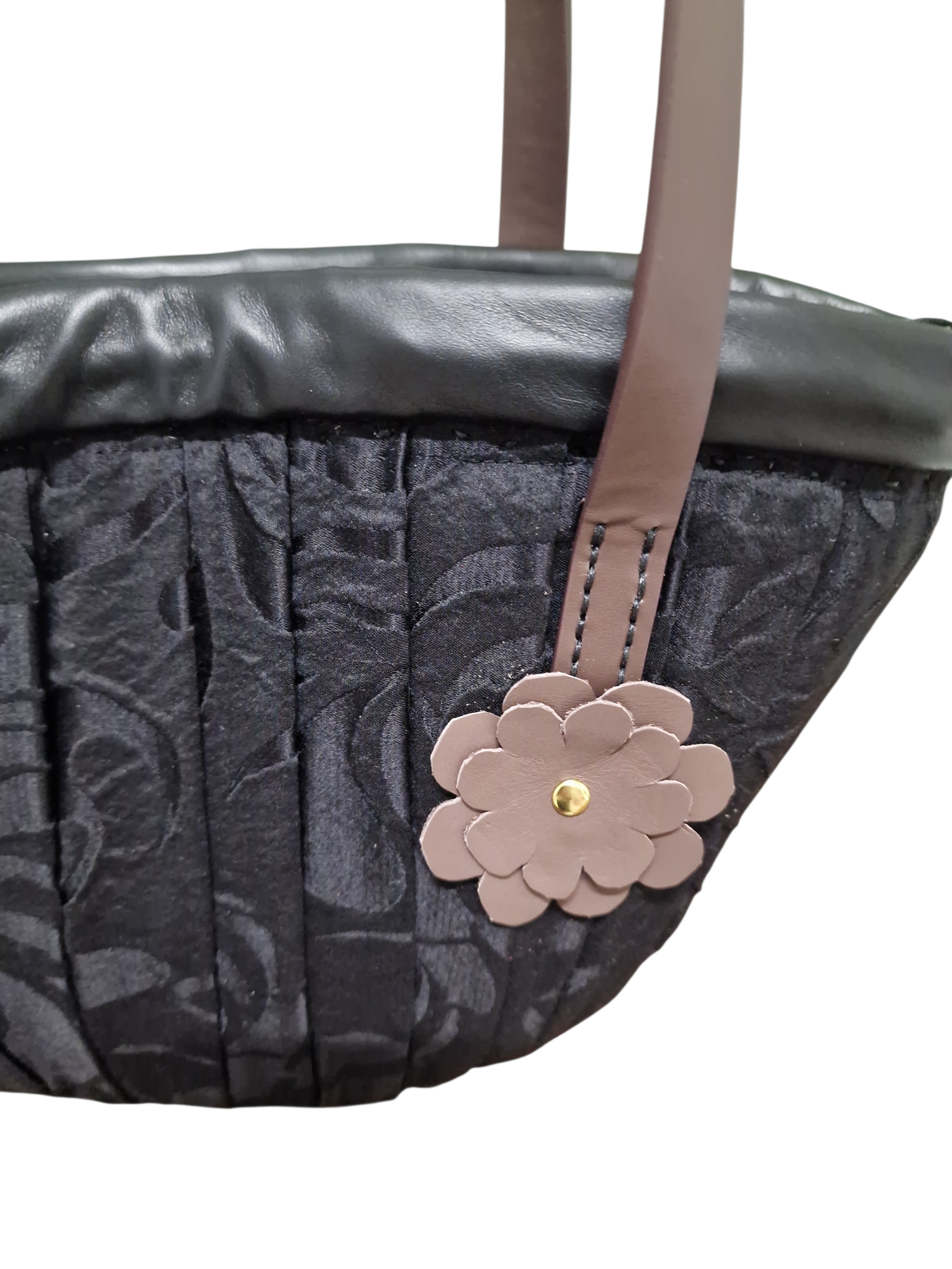 Close-up del fiore Ammuri applicato sulla coffetta Palermo con finiture in pelle e dettagli sartoriali.