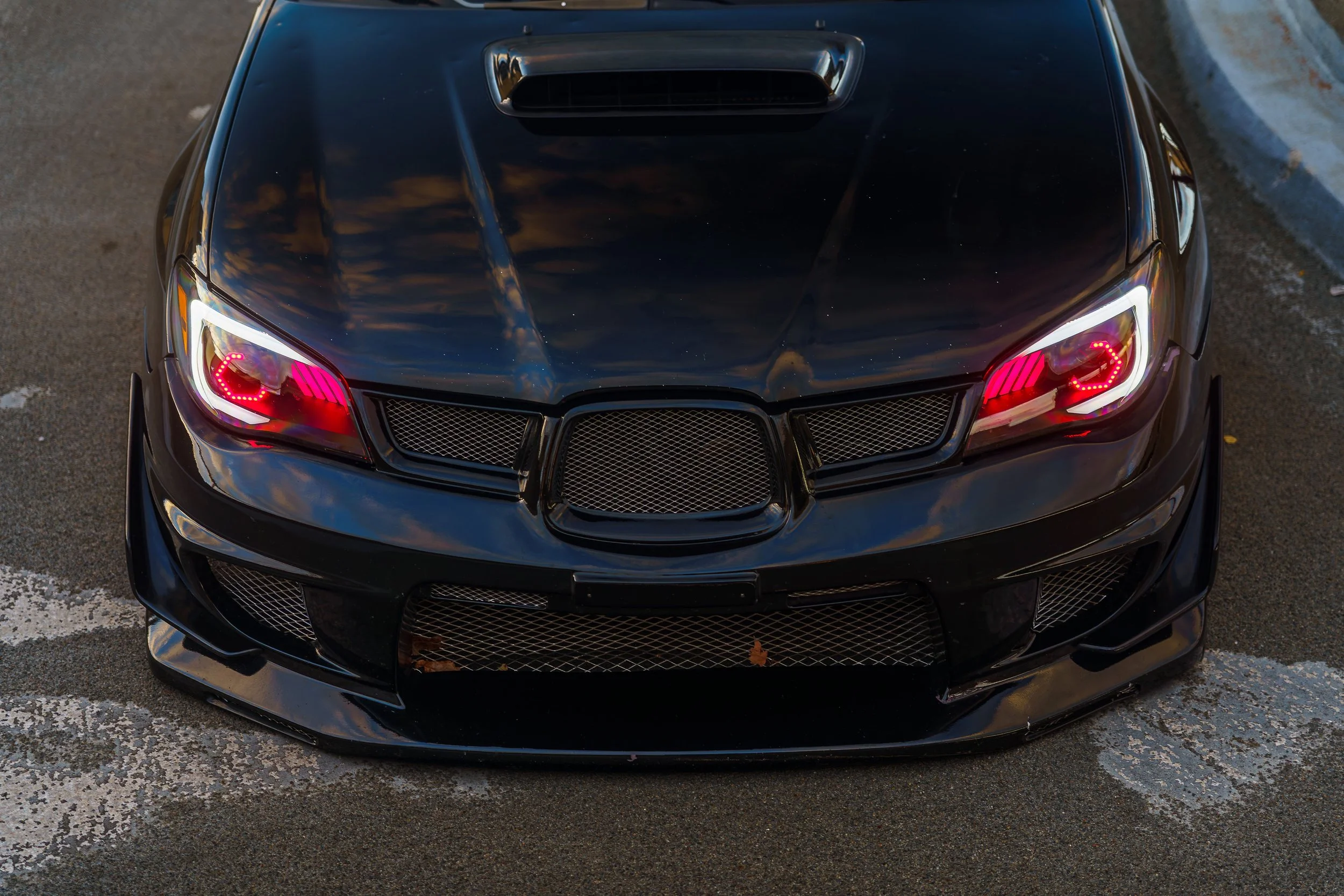 Black sports car with red headlights parked on a street.