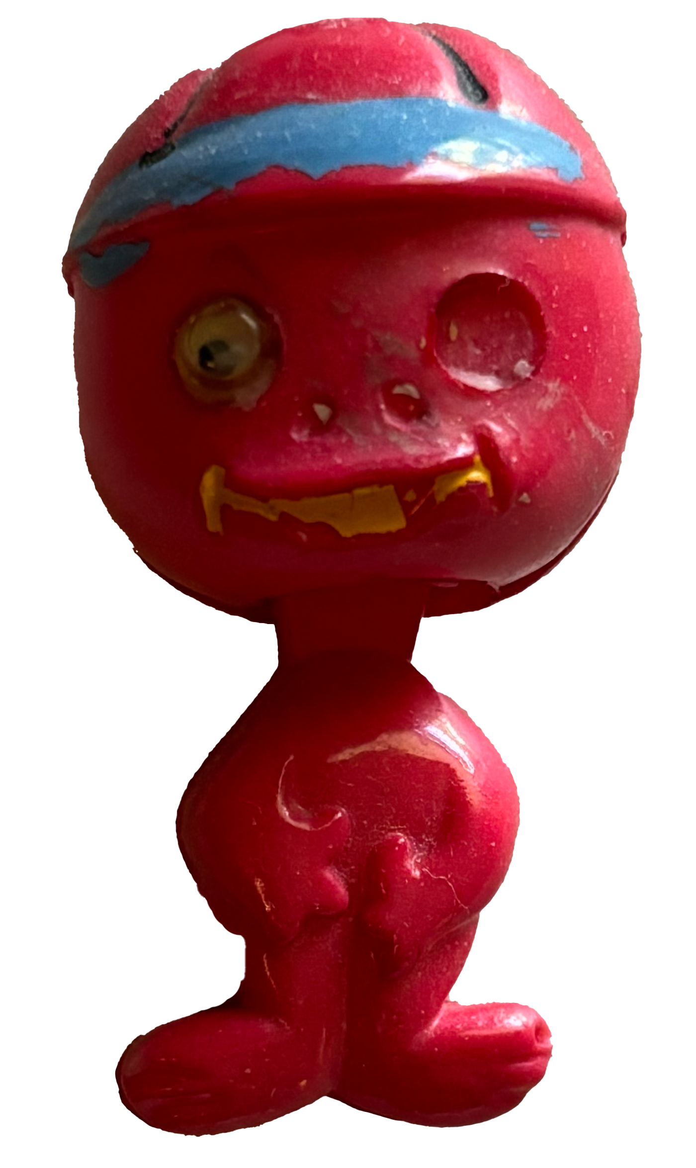 A pink plastic toy with a head resembling a cartoon character, featuring one googly eye, a small hole where another eye should be, a painted blue and pink eyebrow, and a yellow painted mouth. The body is rounded with a simple design.