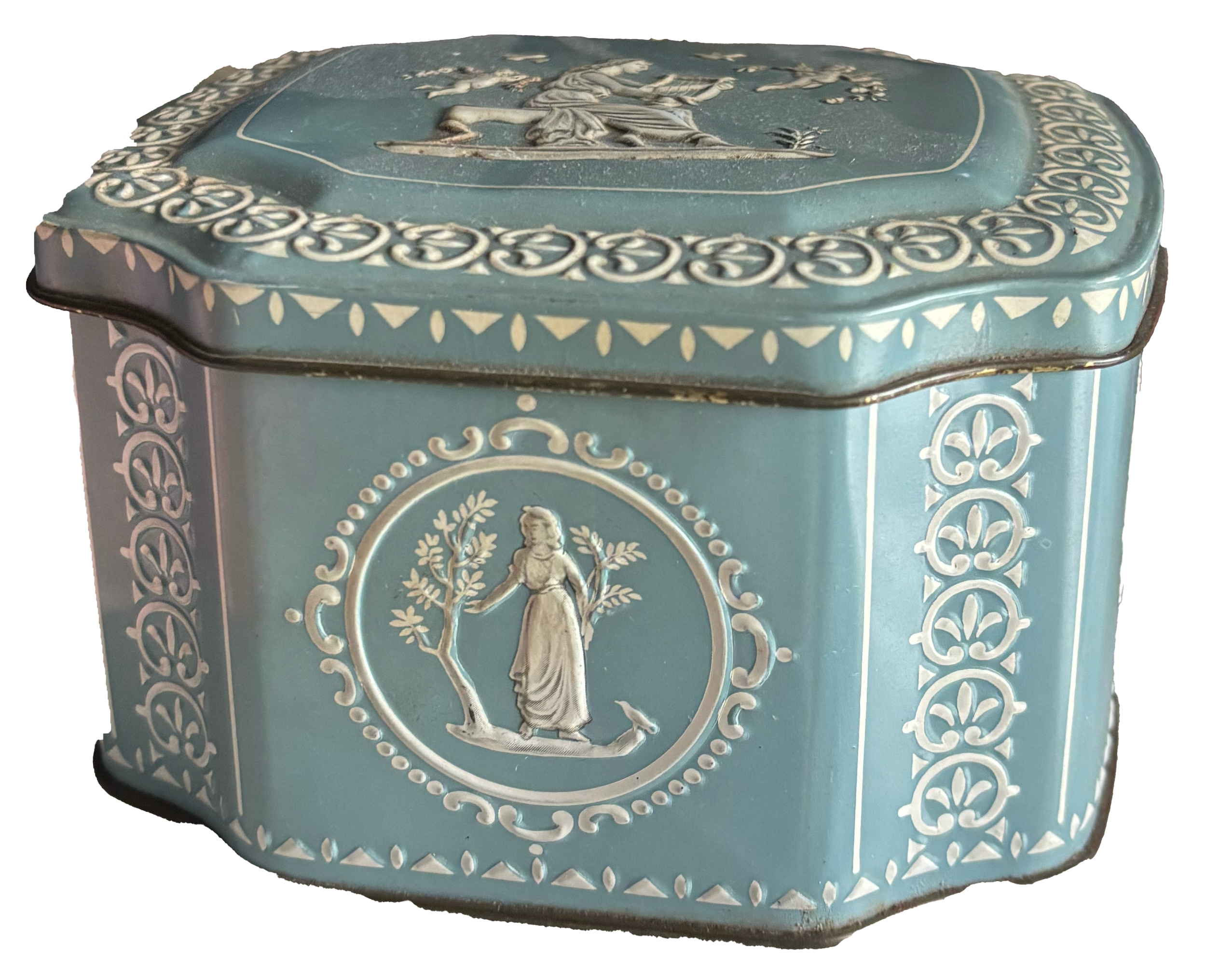 Decorative light blue rectangular tin with white ornate patterns and a central circular emblem of a woman holding trees.