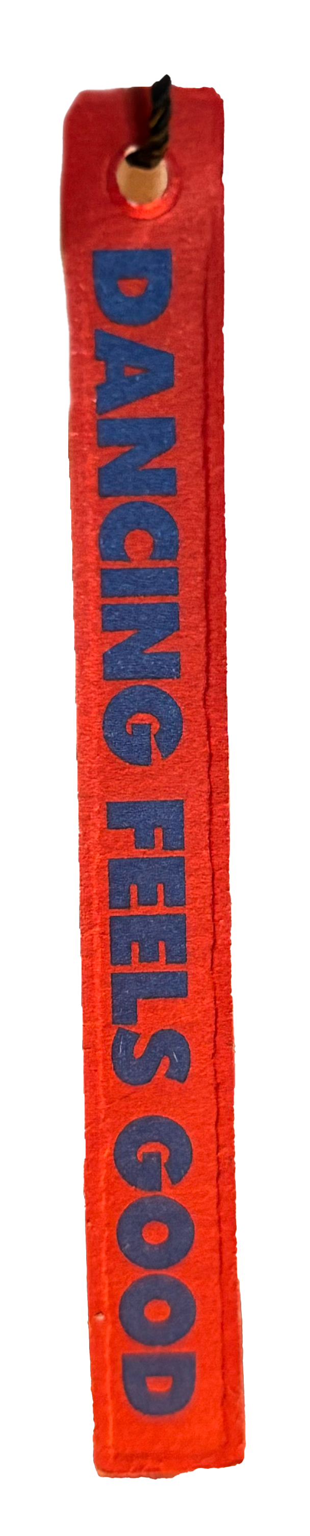 Red fabric label with the phrase "Dancing feels good" printed in blue letters, attached to a black and gold twisted cord at the top.