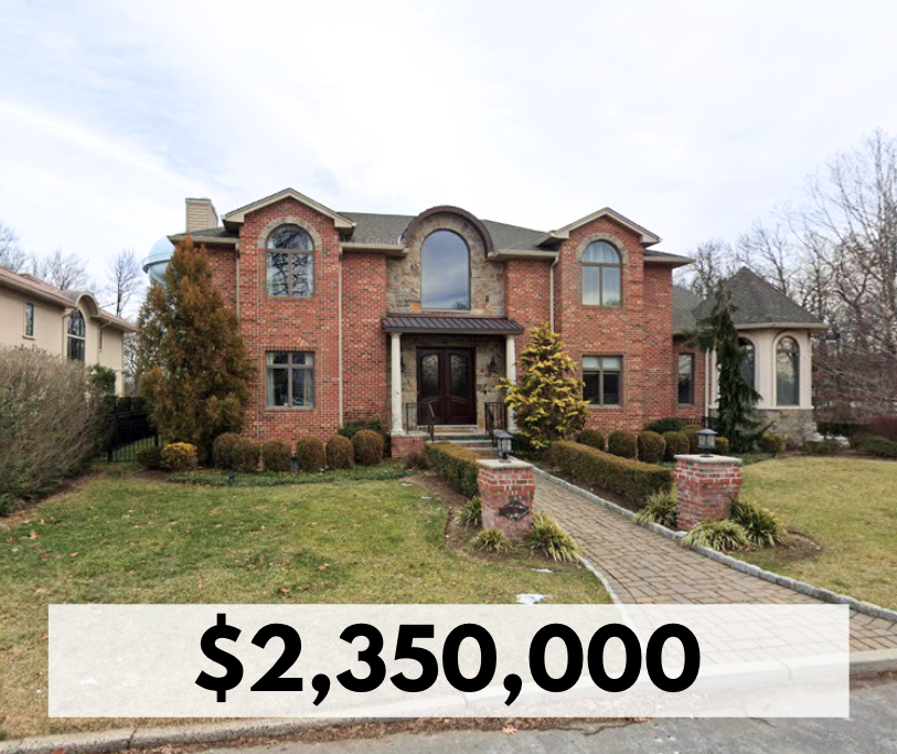 A large two-story brick house with arched and rectangular windows, a front porch, and landscaping including bushes and small trees, with a paved walkway leading to the front door. The house is listed for $2,350,000.