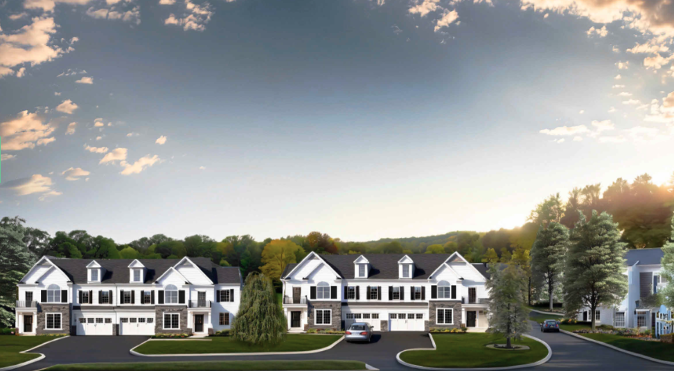 Row of modern white townhouses with black roofs, surrounded by green lawns and trees under a partly cloudy sky.