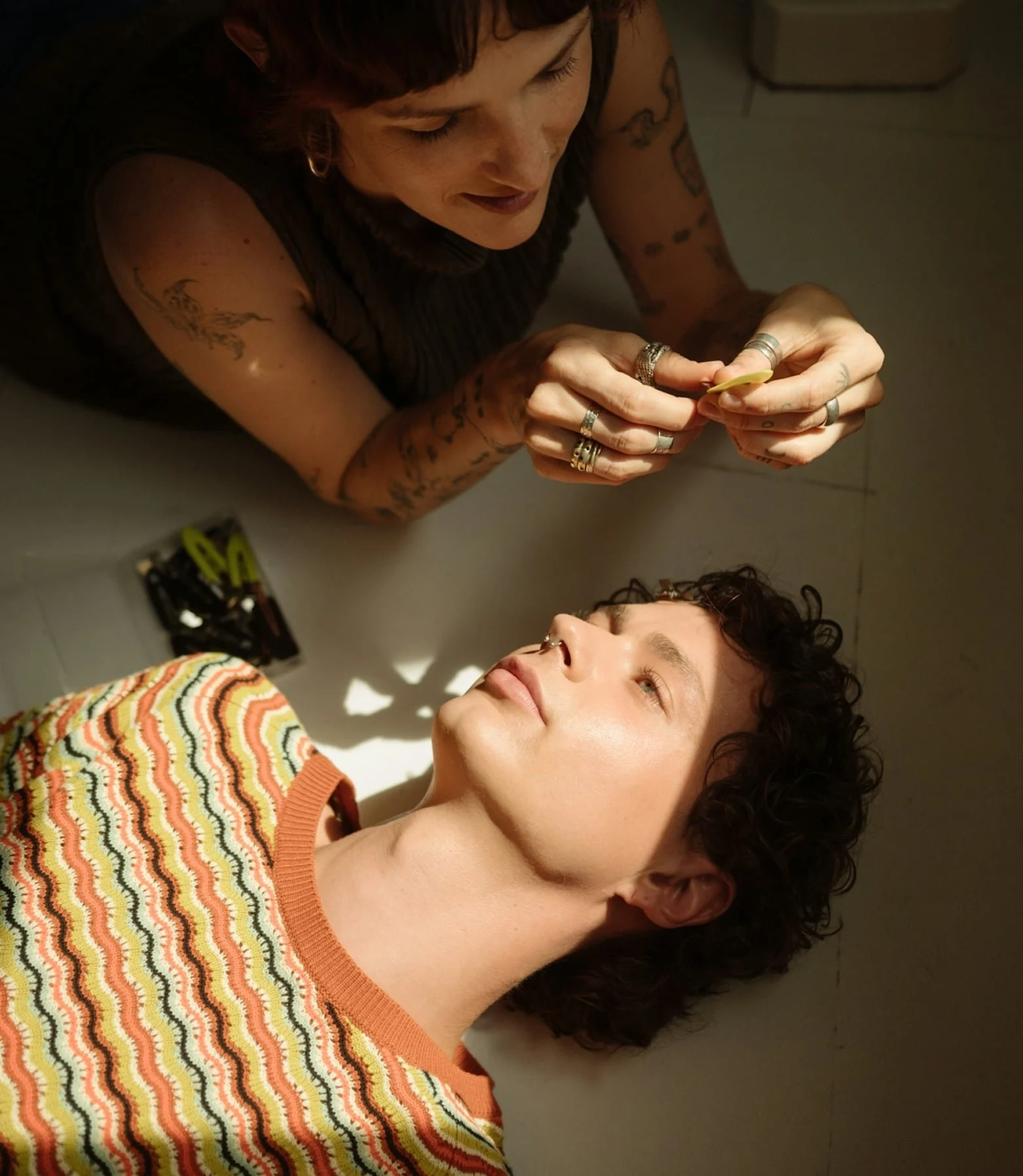 Two people laying on the ground look at one another