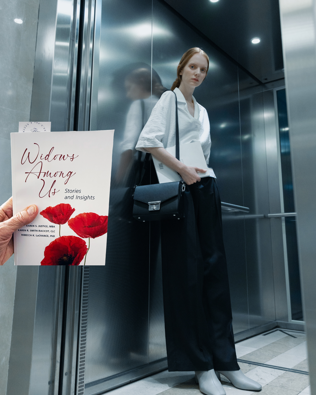 A woman with long red hair standing in an elevator holding her belongings. A person in the foreground holds a book titled "Widows Among Us" with red poppy flowers on the cover.
