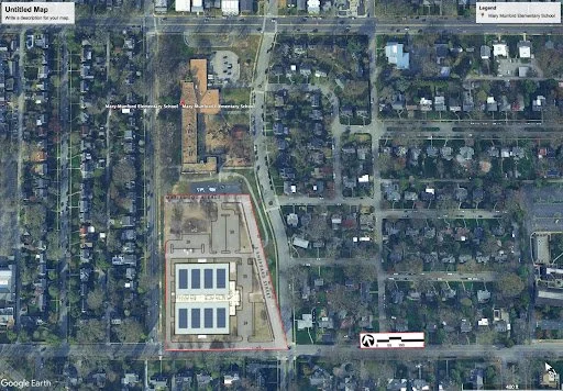 Aerial view of a neighborhood with a large school campus, parking lots, and surrounding residential houses.