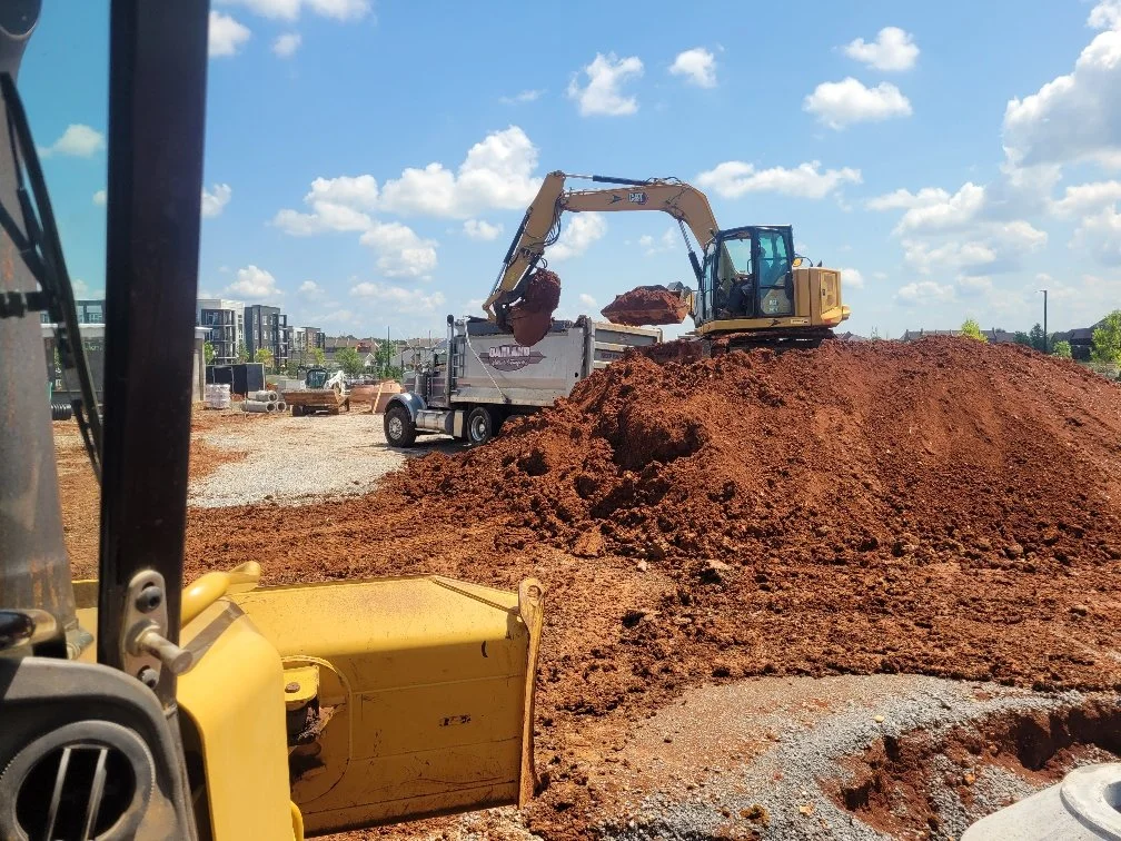 Precision Structures Excavation Services | Pile of dirt with heavy machinery working to remove the dirt.