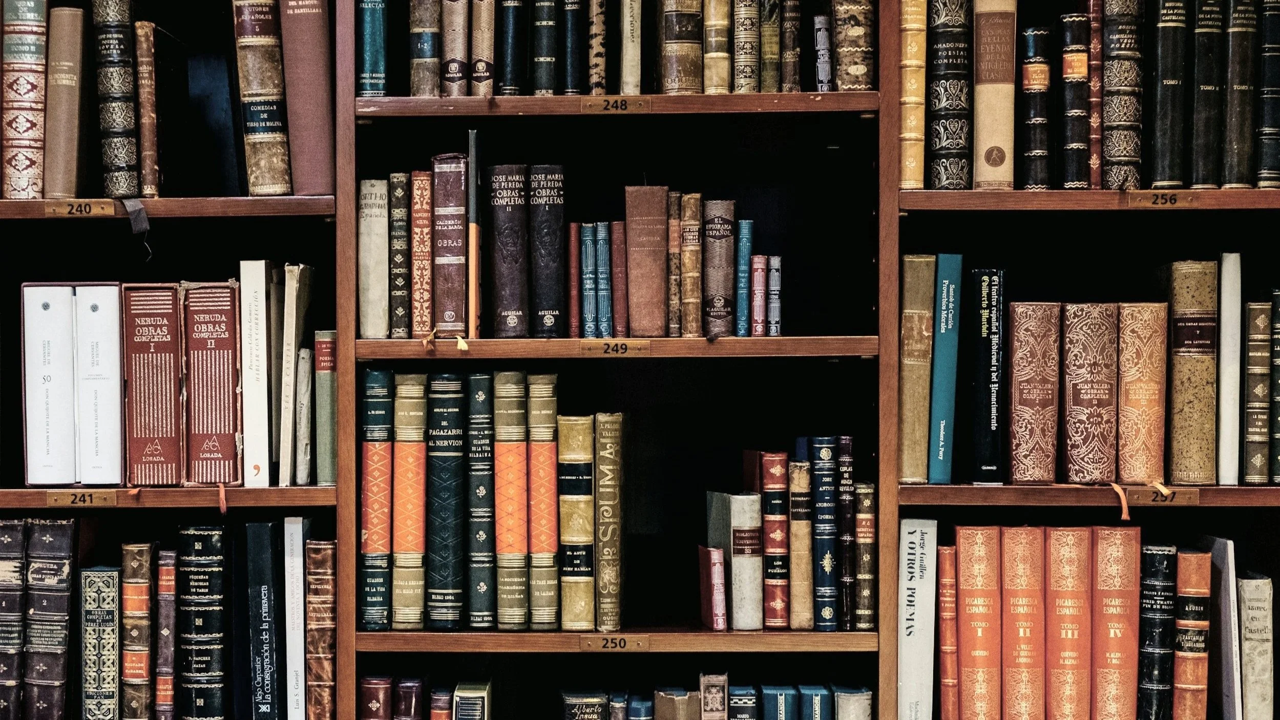 A bookshelf filled with old books organized on multiple shelves with labeled numbers.