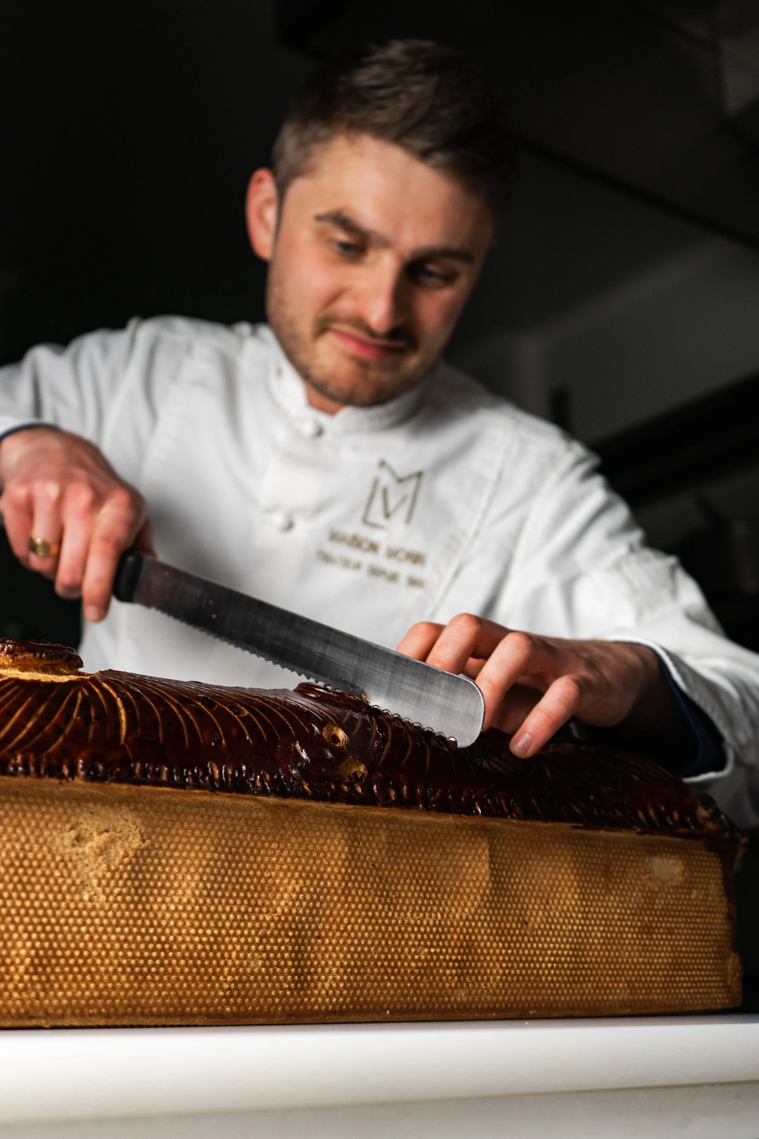 Un chef en train de couper un poisson sur un plan de travail.