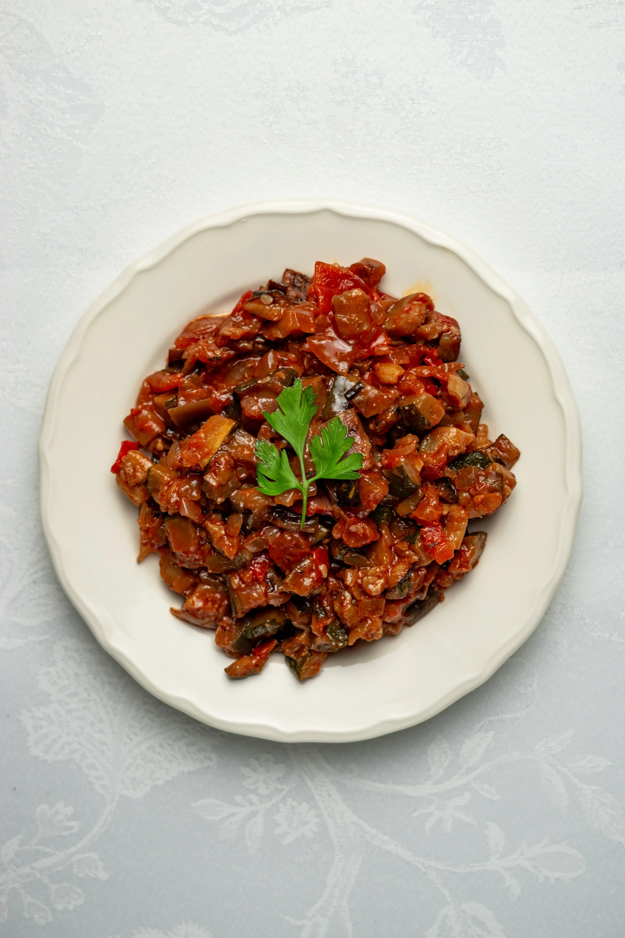 Ragoût de légumes dans une assiette blanche avec une garniture de persil en haut au centre.