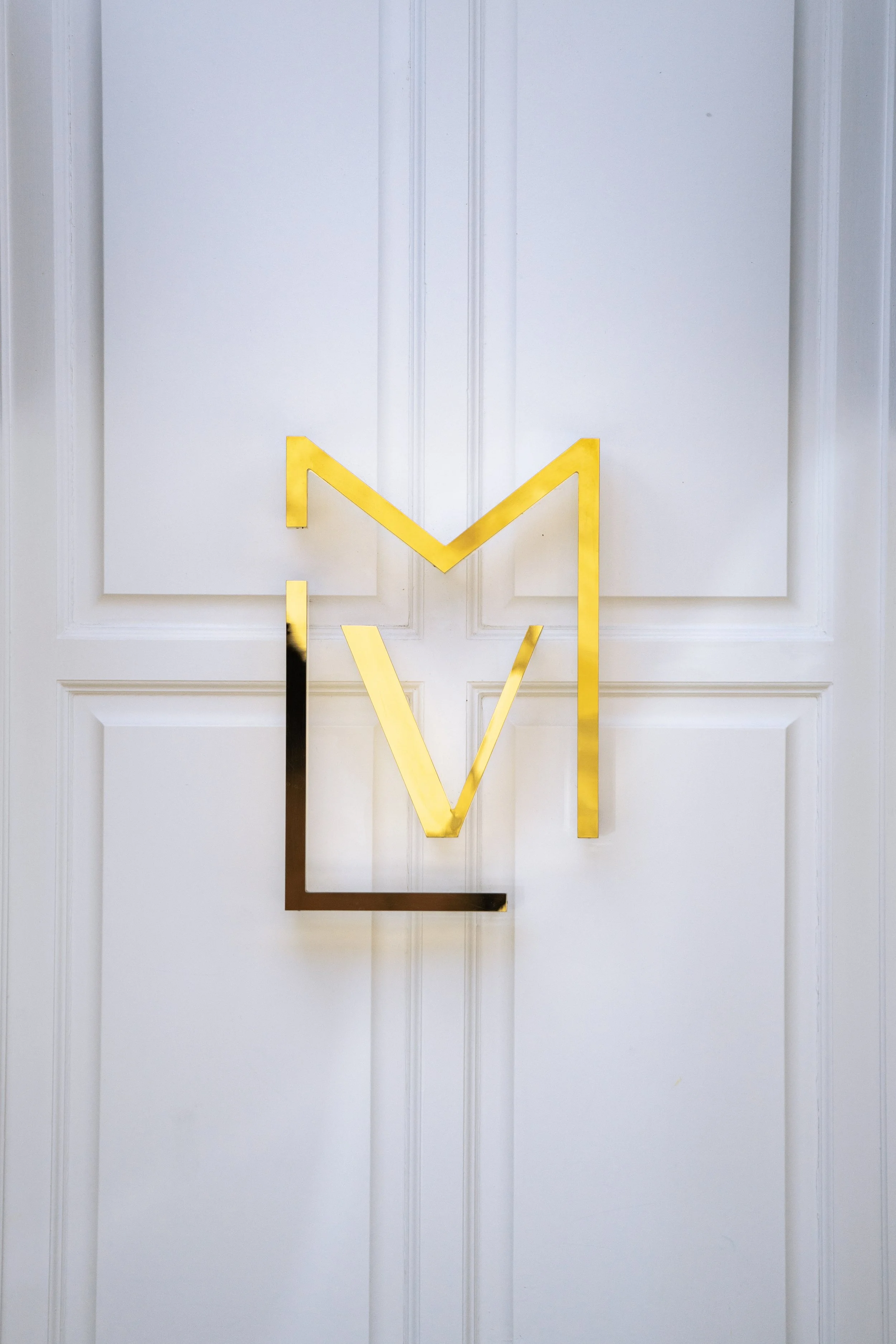 Une horloge murale moderne en forme de lettres dorées et noires fixée sur une porte blanche