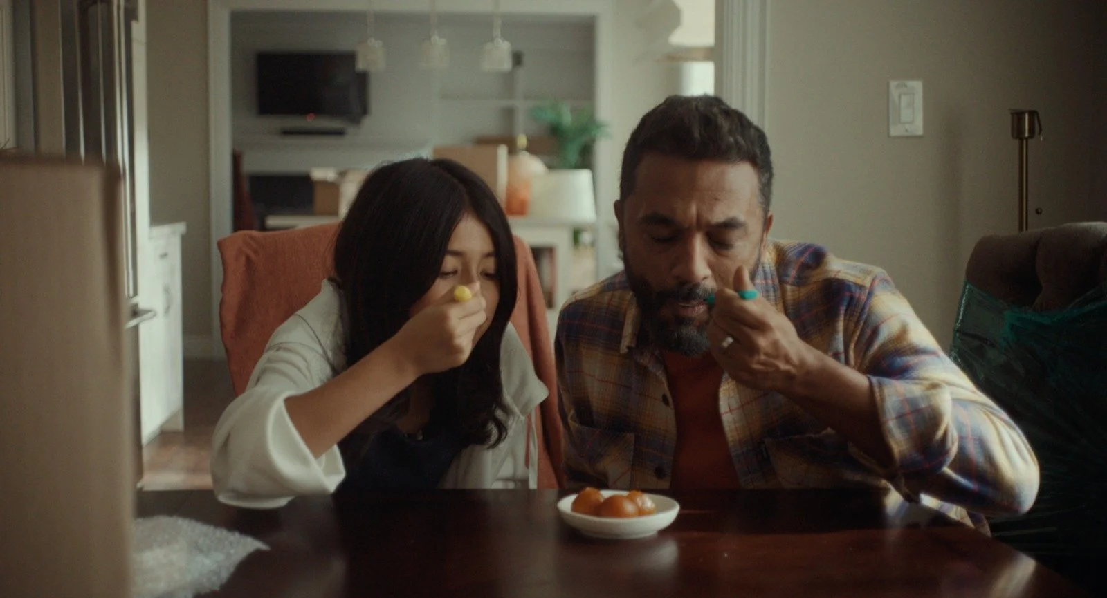 A girl and a man are sitting at a table, eating food from small bowls.