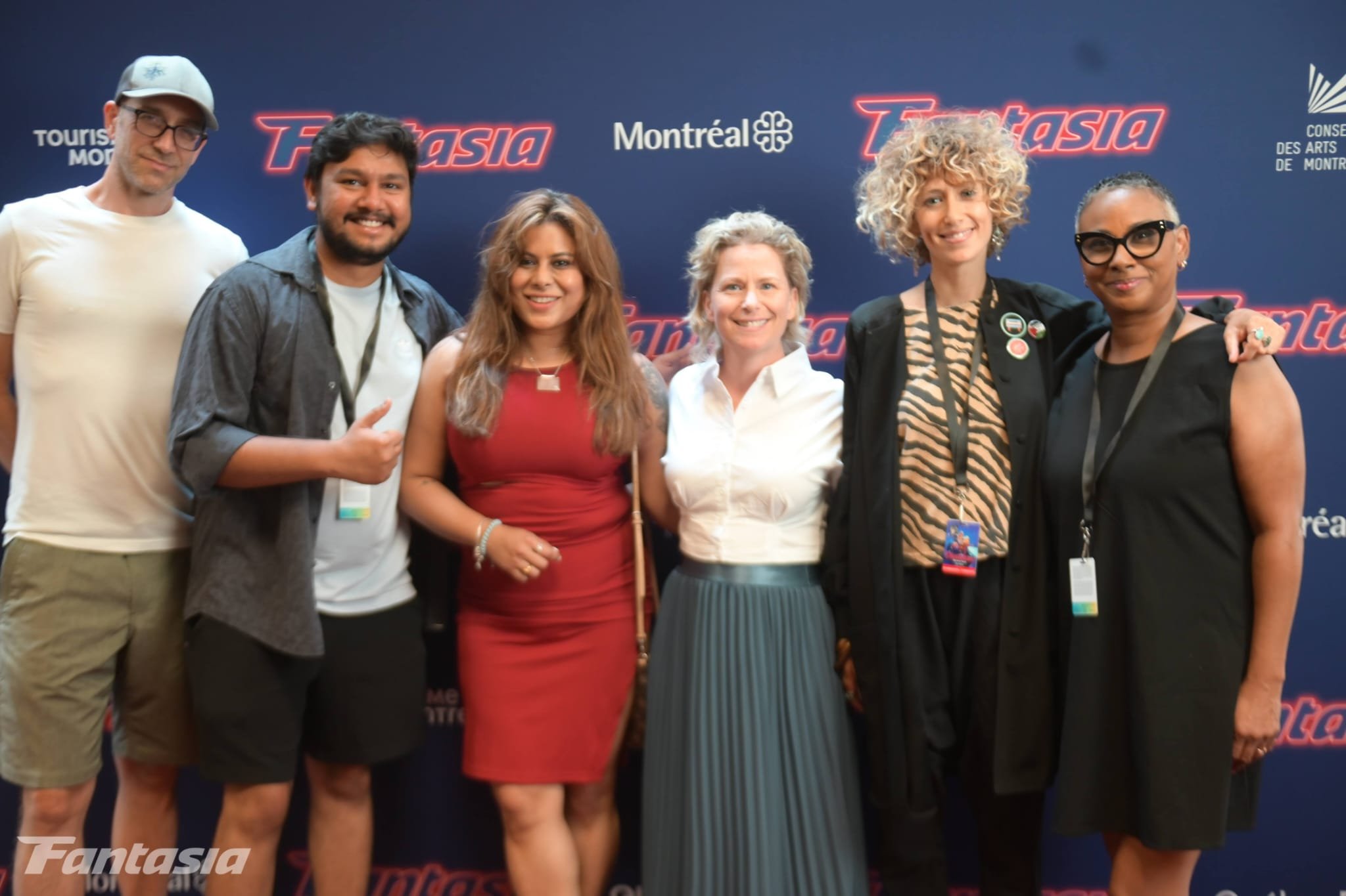 Group of six diverse people standing together in front of a backdrop with logos for Fantasia, Montreal, and Conseil des Arts de Montreal. They are smiling and posing for the photo, dressed casually.