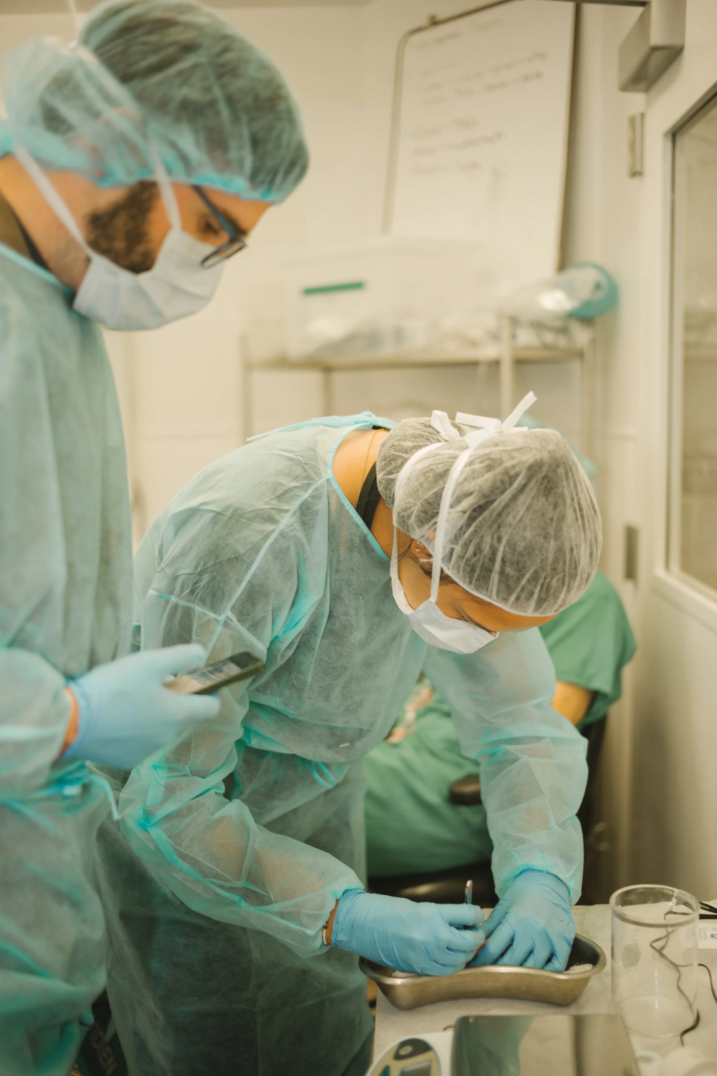 Medical professionals in surgical attire performing a procedure in an operating room.