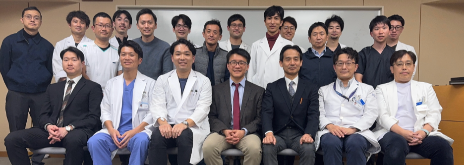 Group of medical professionals and researchers posing for a photo in a conference room or hospital setting.