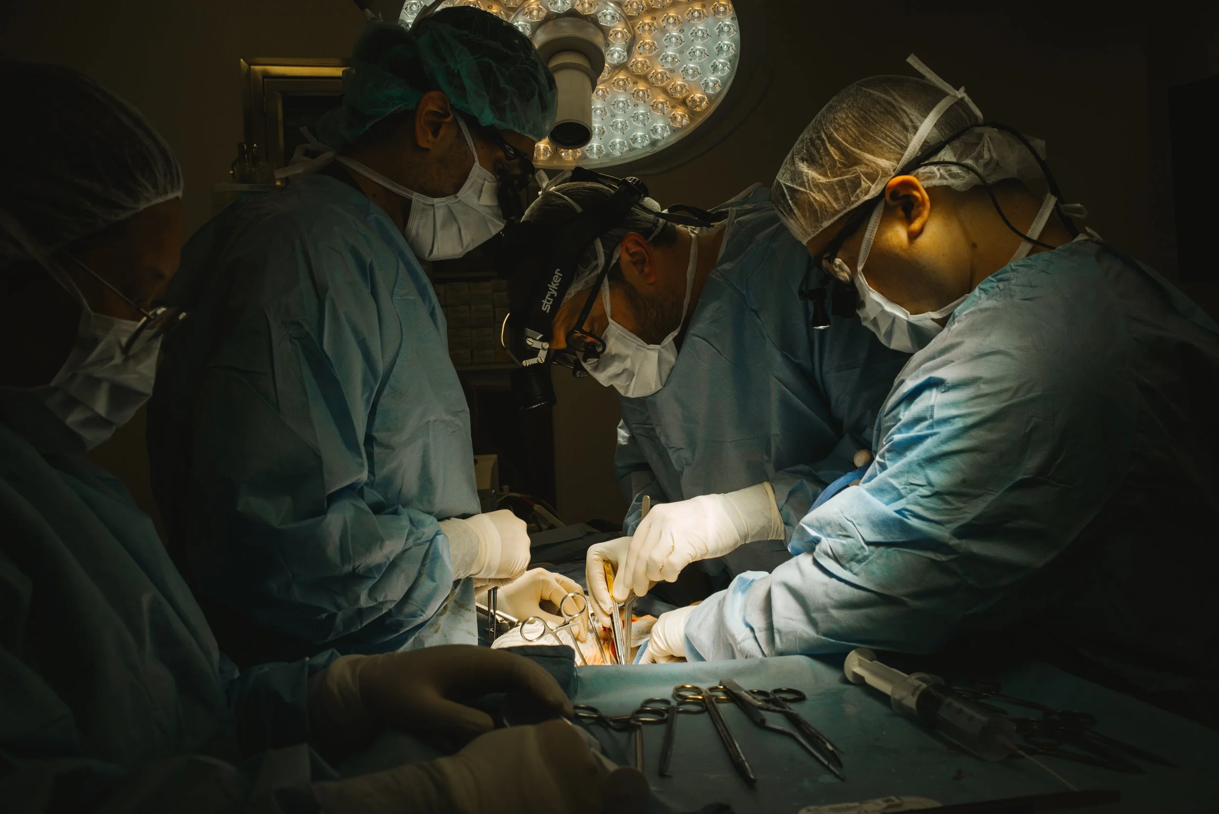 Medical team performing surgery in an operating room, focused on the procedure under bright surgical lights.