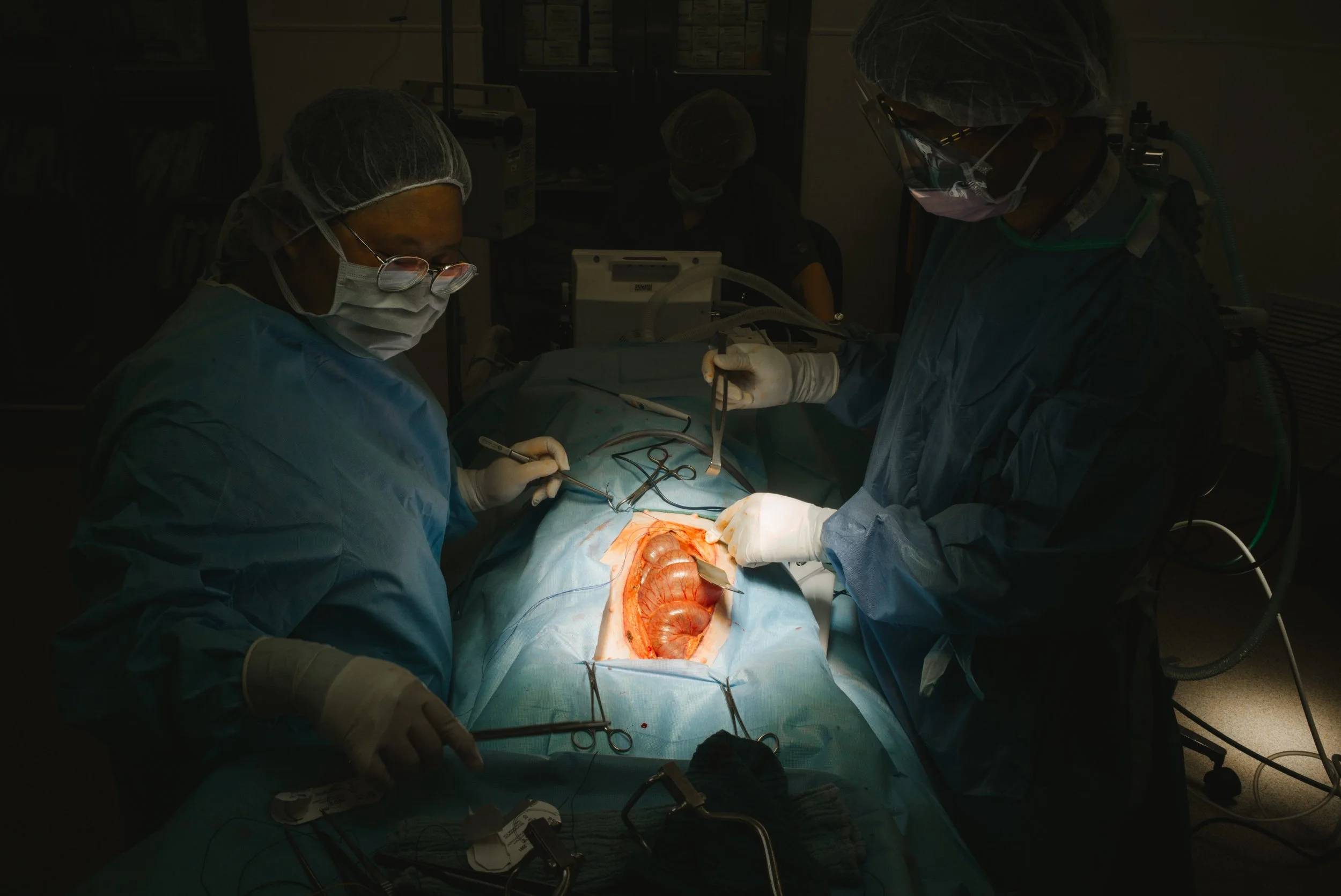 Surgeons performing an operation in an operating room, with the patient and medical tools visible.