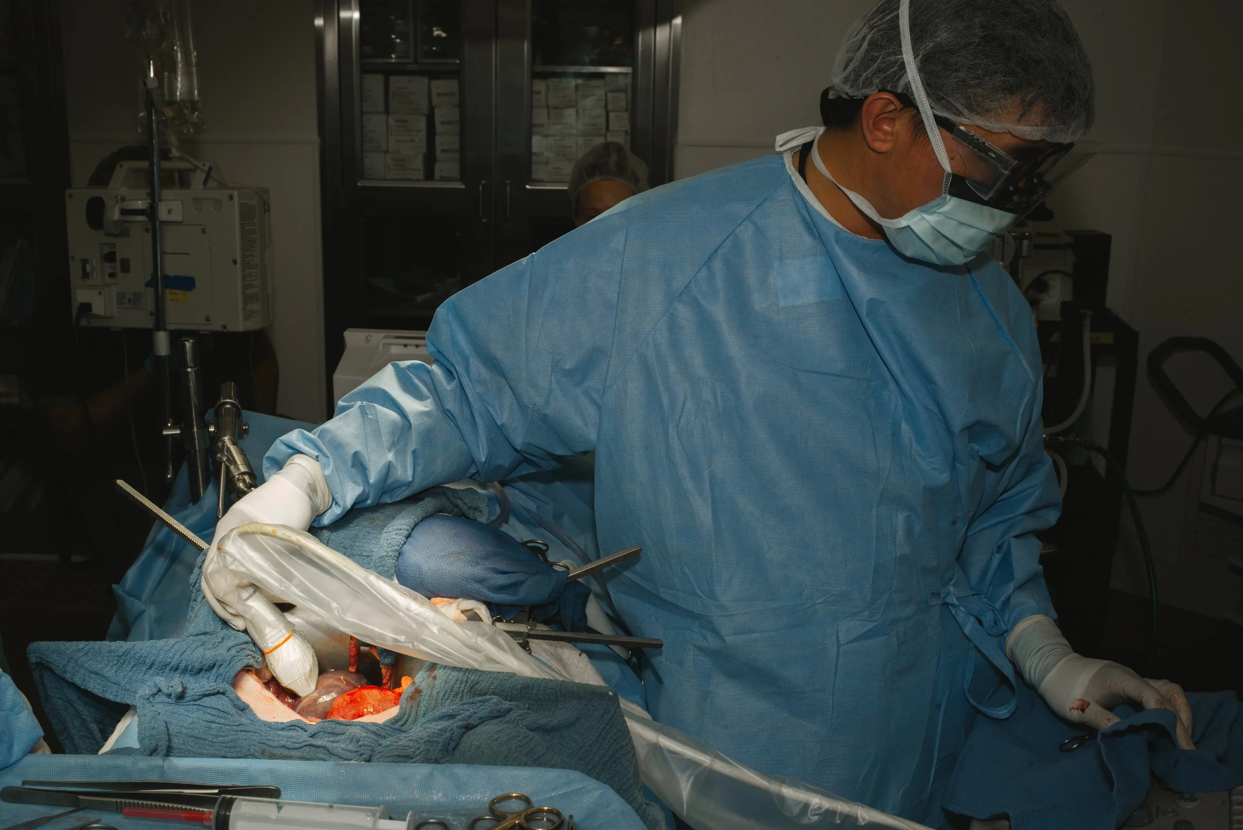 Surgeon performing an operation in an operating room, with medical tools and equipment visible.