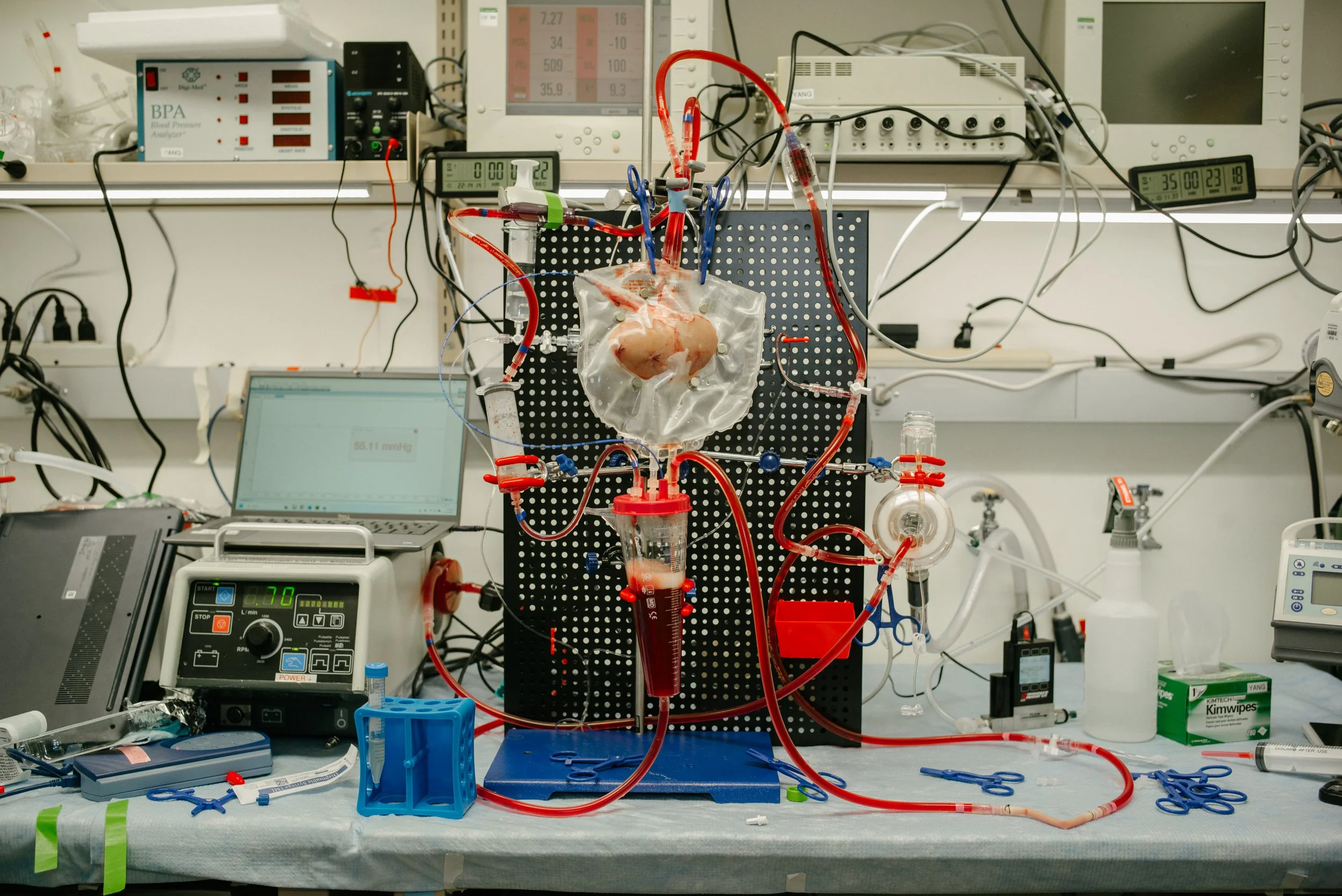 A laboratory setup for a mechanical heart experiment with tubing, a chamber, and electronic equipment on a workbench.