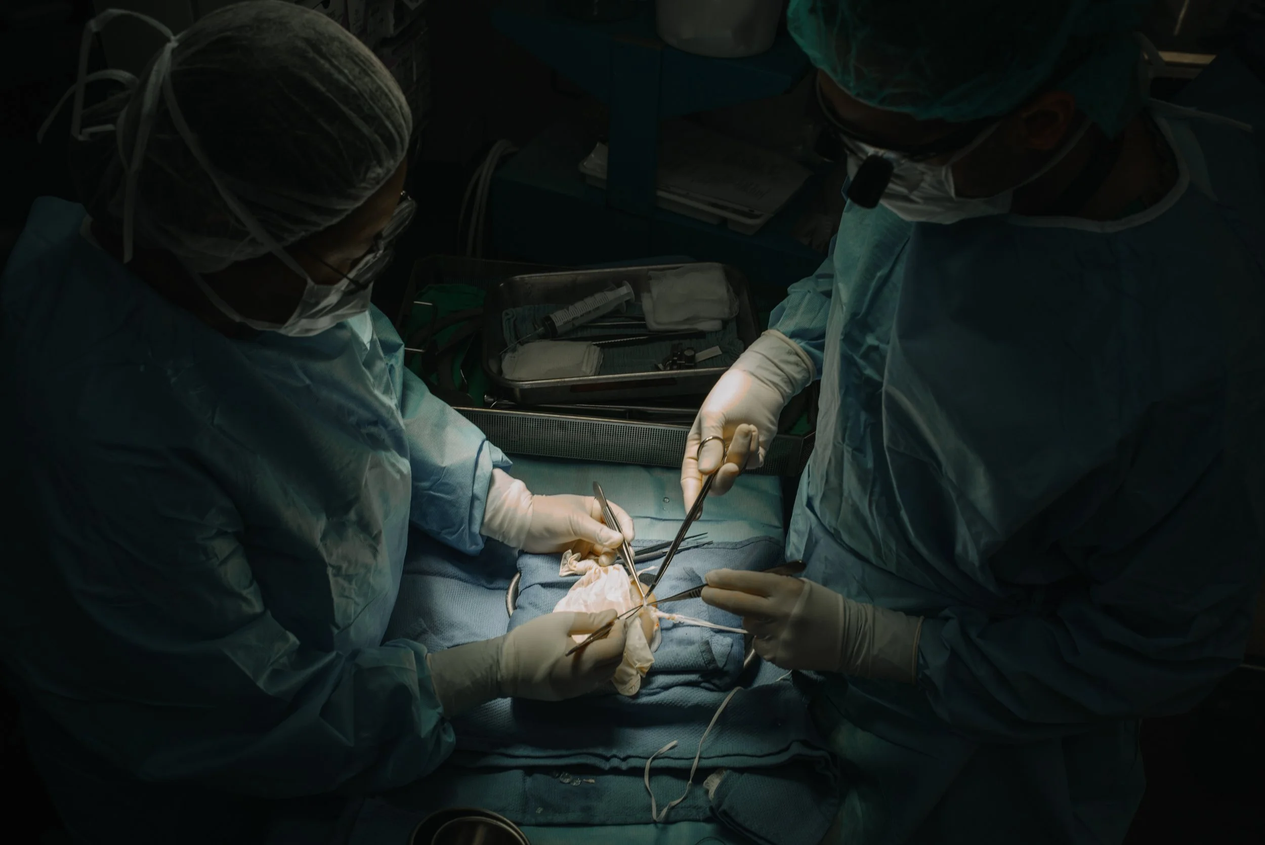 Surgeons performing an operation in an operating room with surgical tools and equipment.