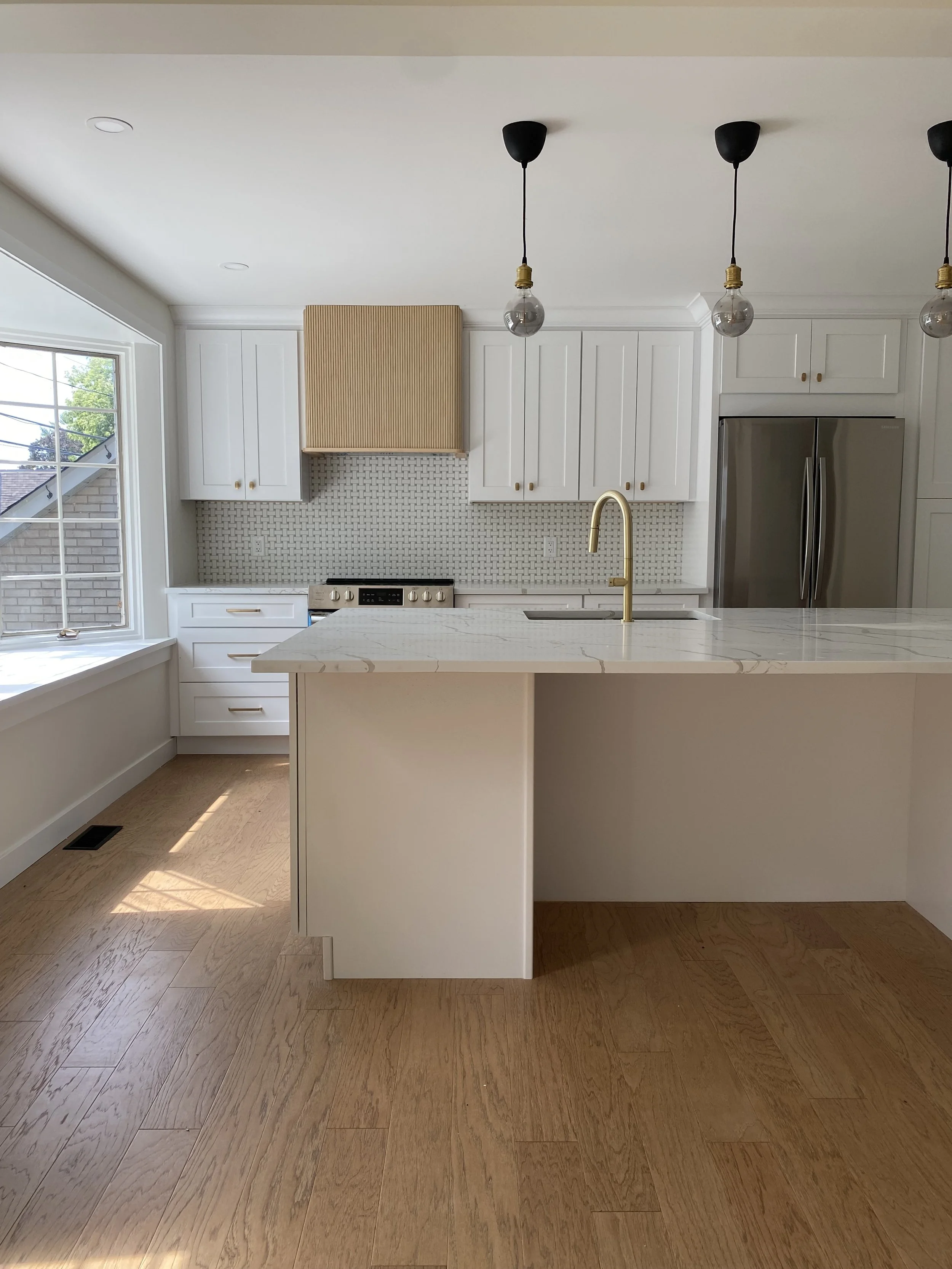 modern bathroom with a free-standing bathtub, glass-enclosed shower, two windows with blinds, a black ladder towel rack, a framed minimalist line art portrait on the wall, a small wooden stool, and decorative towels and plants.