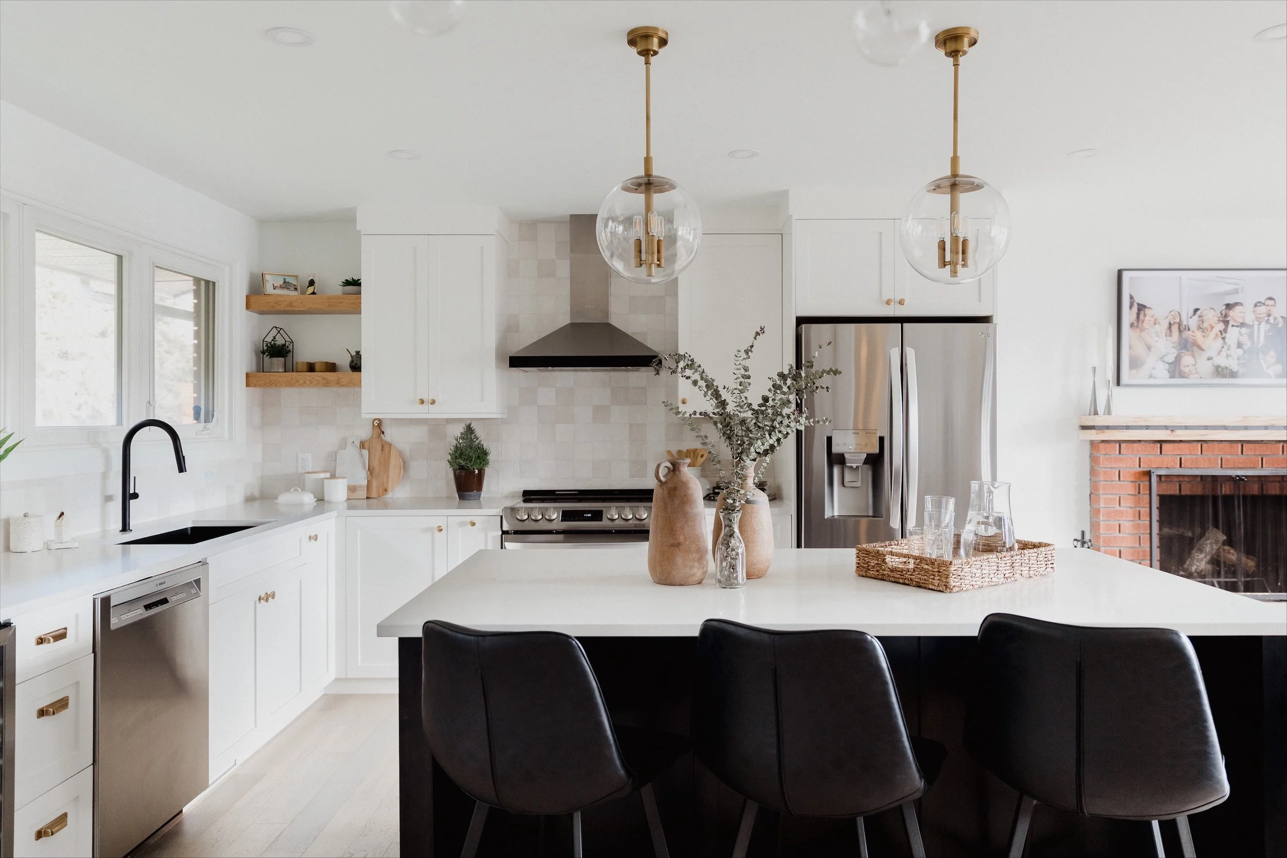 A cozy bathroom setting with a bathtub, a wicker basket filled with white towels and a bathrobe, slippers on the floor, a window, and a tray with a glass of white wine, a book, and a flower on the bathtub's edge.
