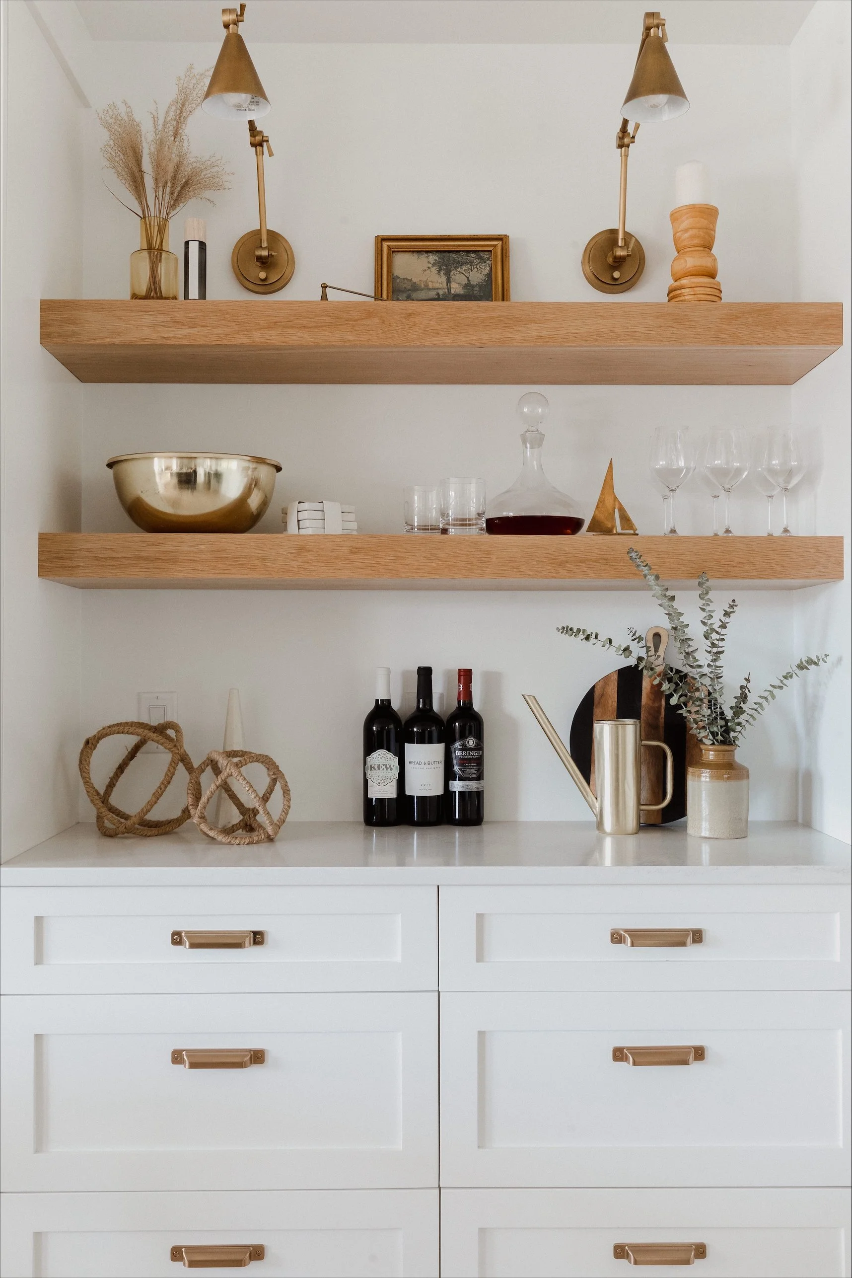 Modern walk-in shower with glass doors, two showerheads, a small wooden stool, and a built-in niche with a plant hanging
