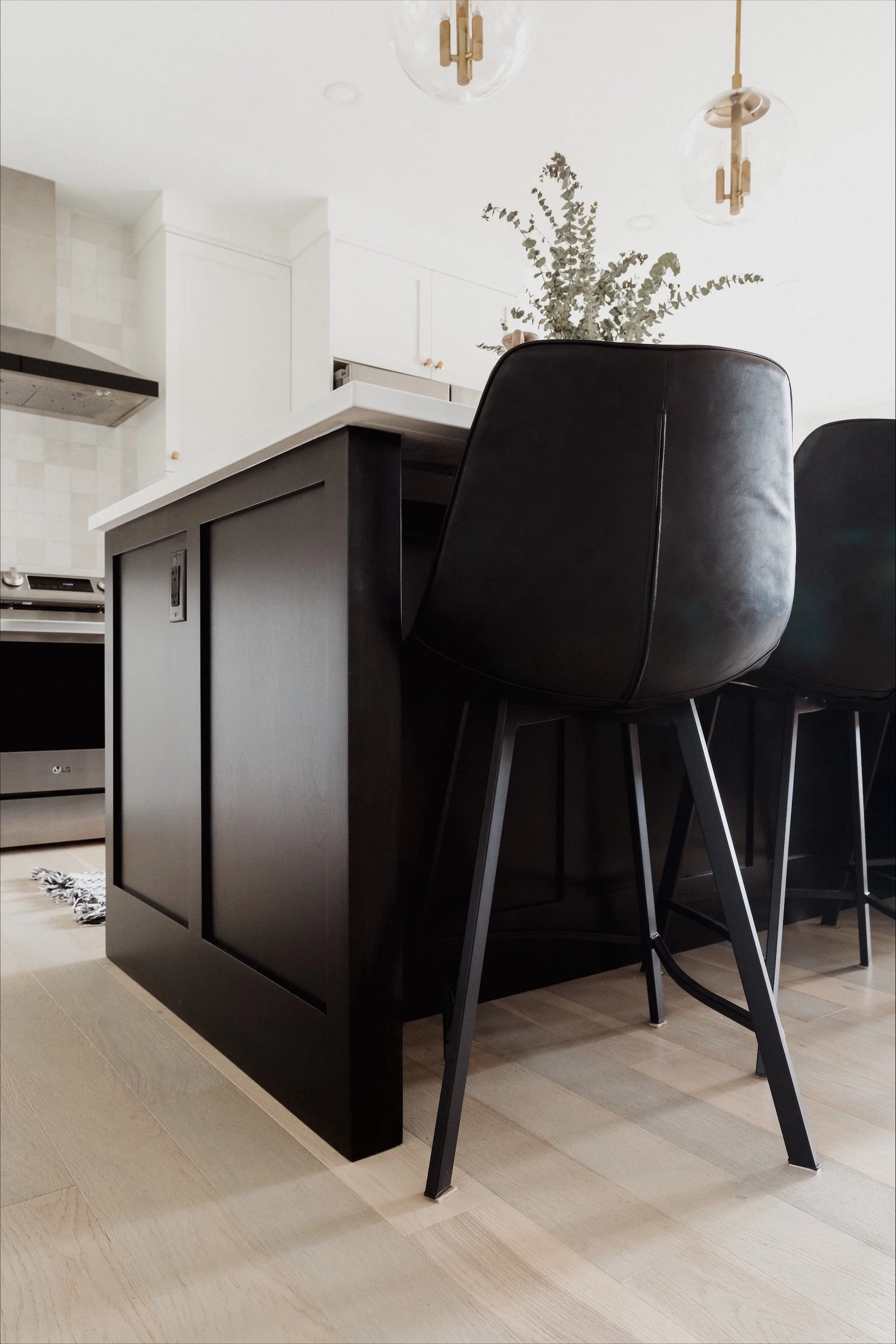 Close-up of a modern wall sconce with a brass finish and ribbed glass shade mounted on a white wall near a mirror in a bathroom.