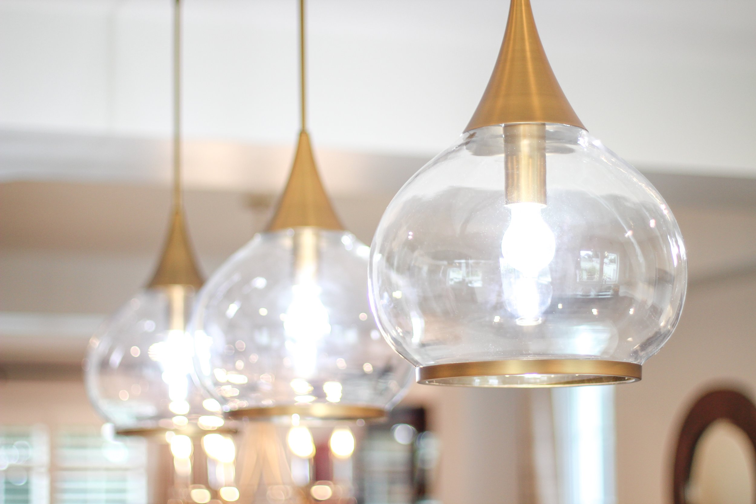Three modern pendant lights with glass globes and brass details hanging indoors.
