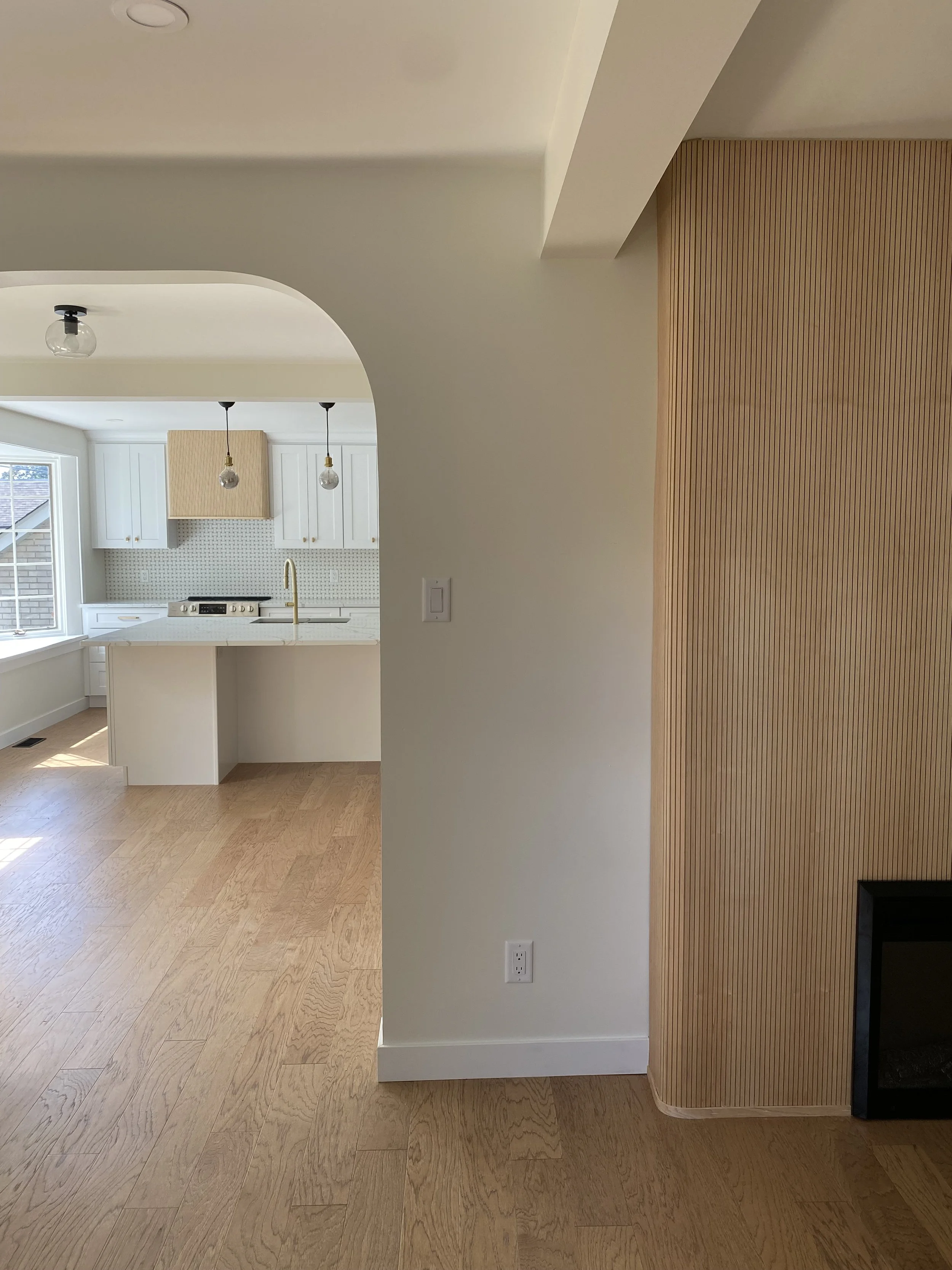 Modern walk-in shower with glass doors, two showerheads, a small wooden stool, and a built-in niche with a plant hanging