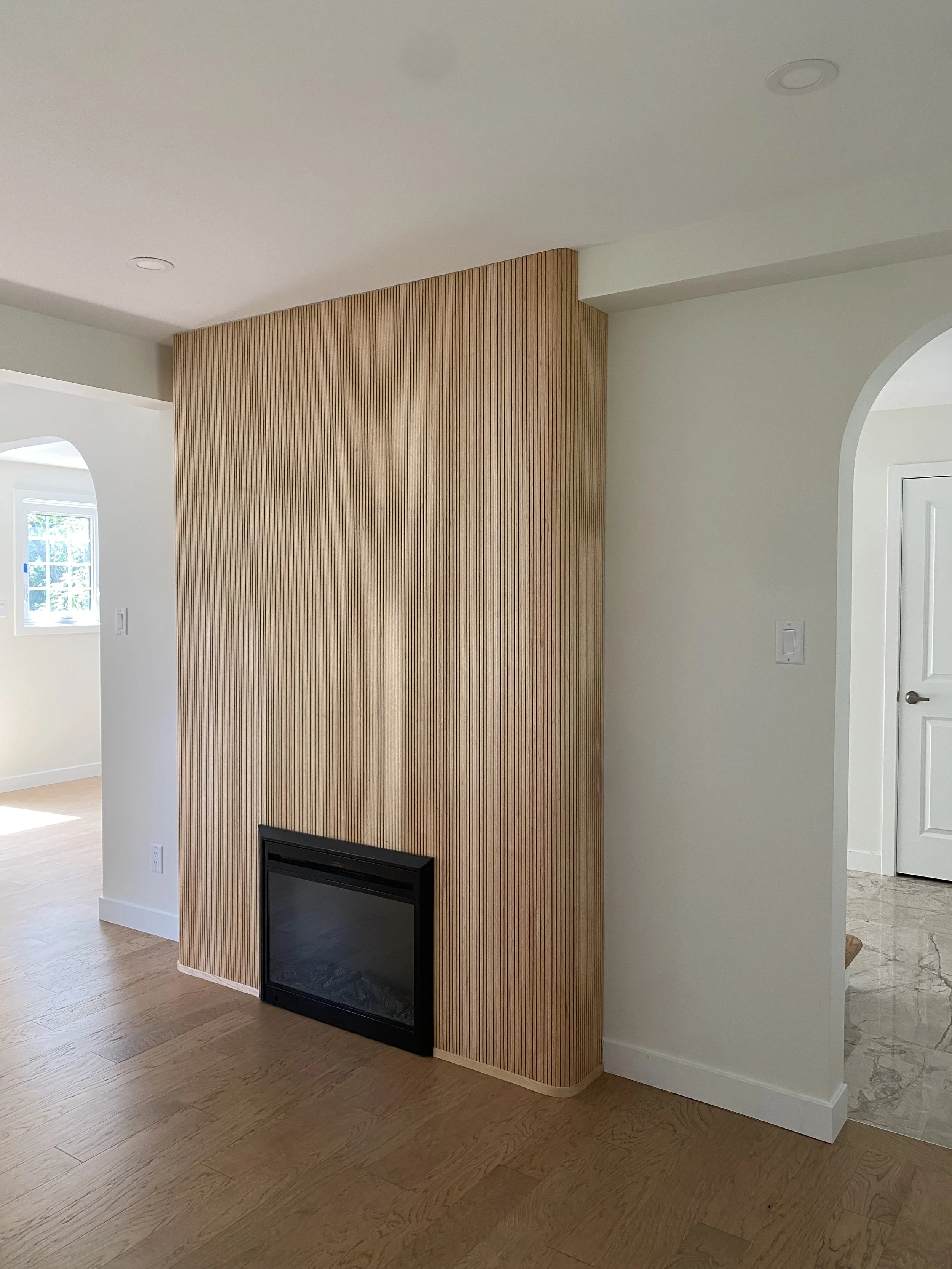 A modern bathroom with a double vanity, two mirrors, gold fixtures, and light fixtures on each side of the mirrors. The vanity has grey cabinets and a white countertop, with decor and toiletries on it.