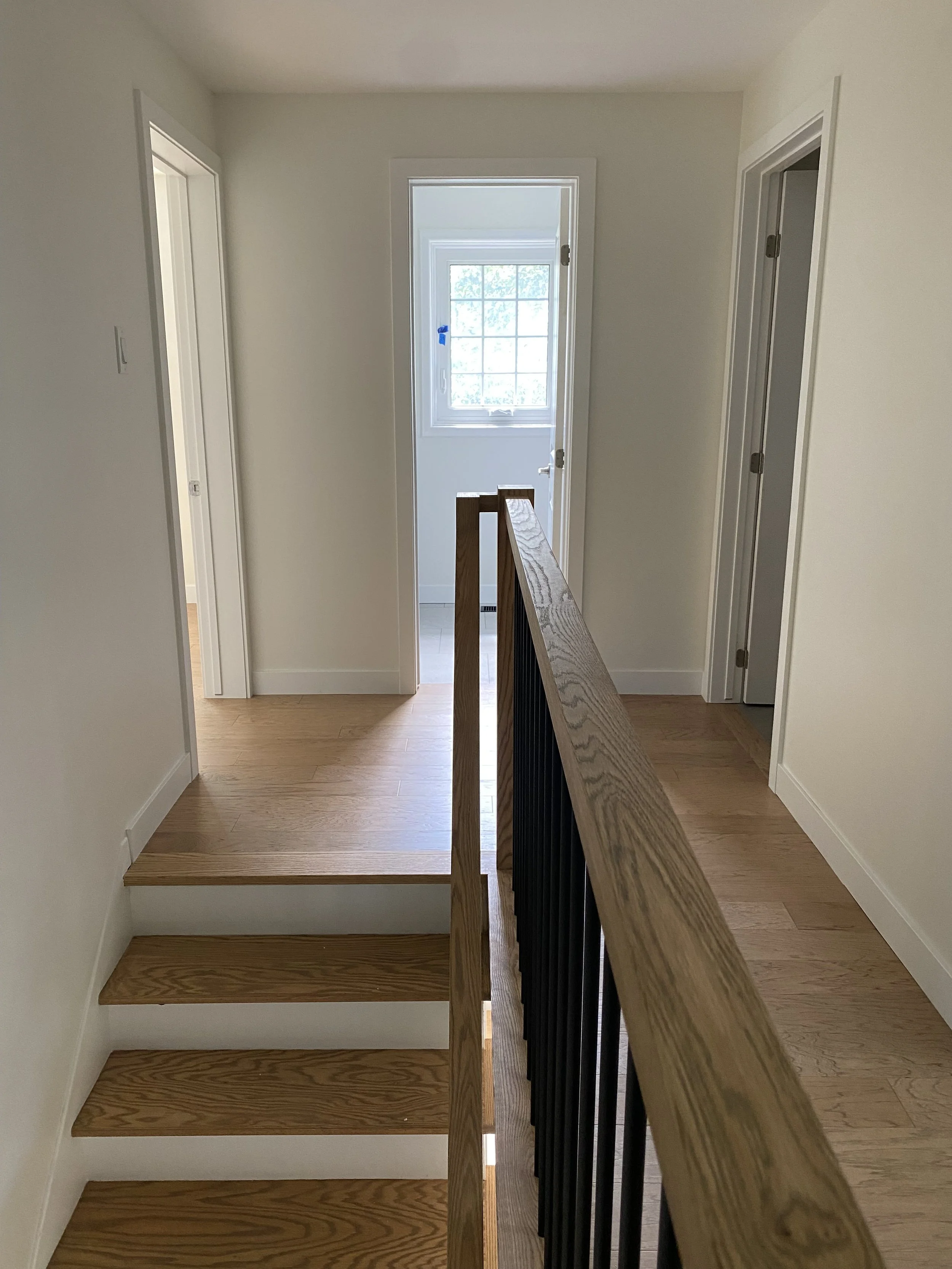 Decorative beige vase with lavender flowers, skincare products, and a spray bottle on a wooden tray, against a white wall with mirrors.