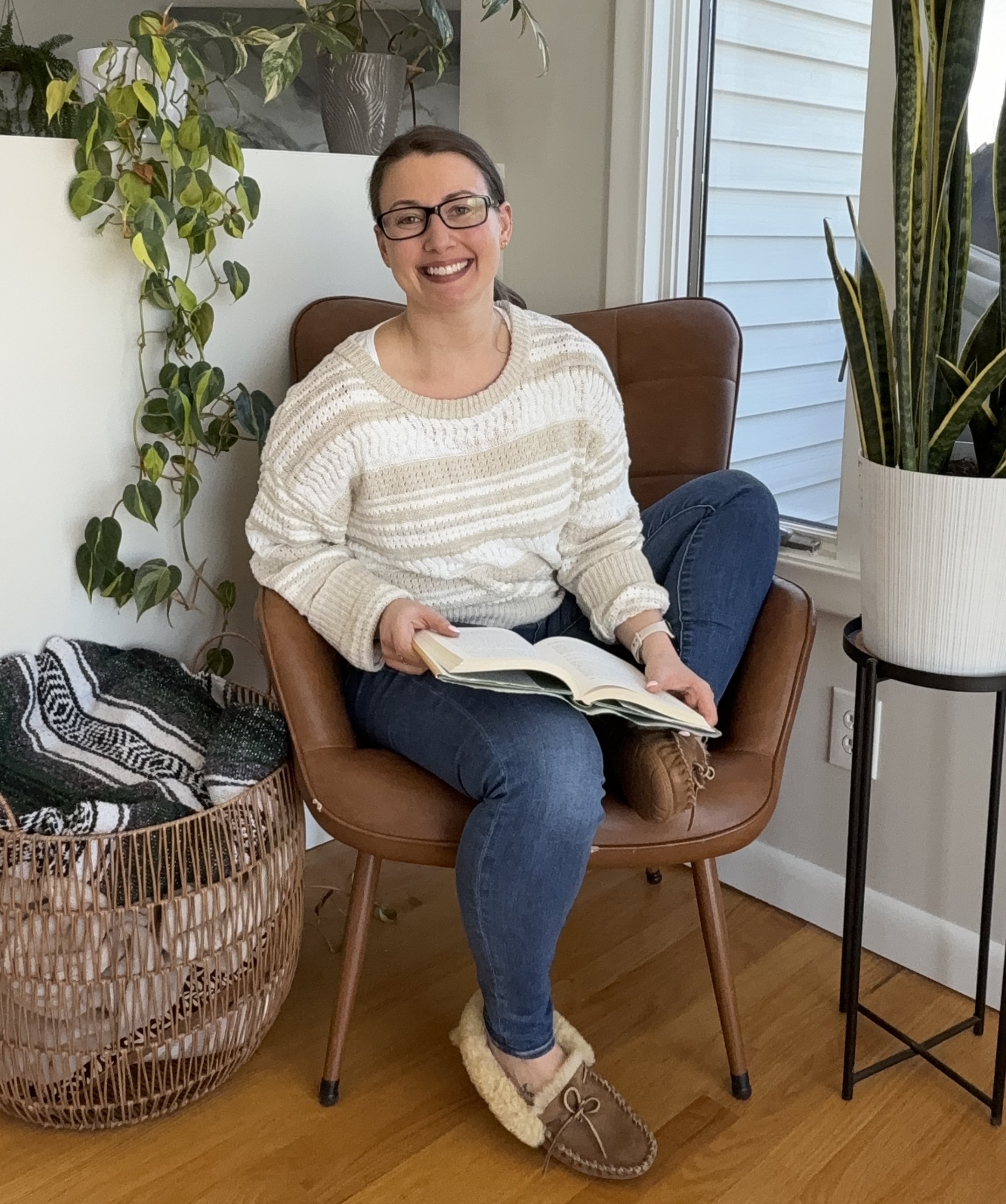 Amberleigh Maida seated in a calm office setting, welcoming new clients to reach out for pain reprocessing therapy and life coaching support.