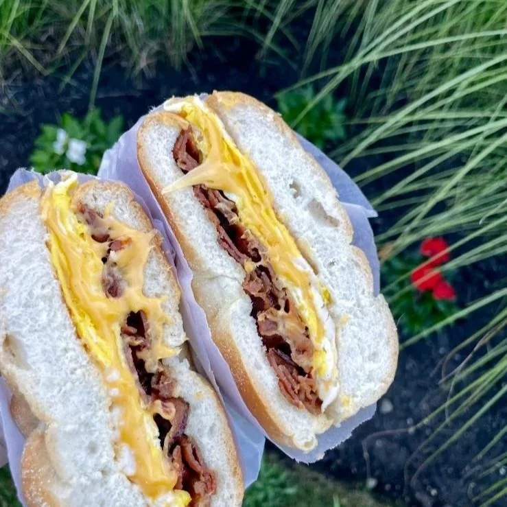 Halved breakfast sandwich with eggs, bacon, and cheese on a bun.