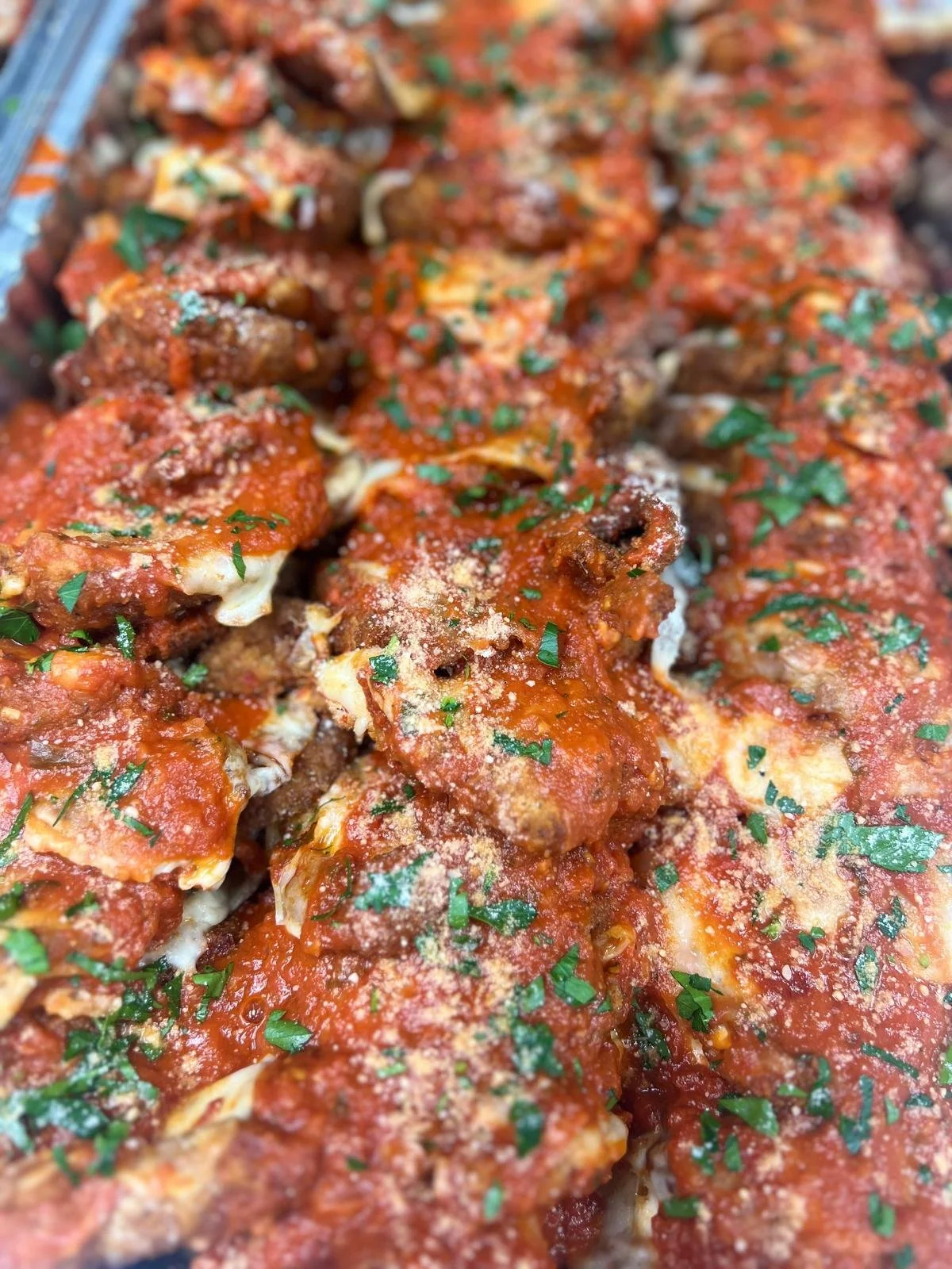 Close-up of cooked spaghetti with tomato sauce, sprinkled with grated cheese and chopped herbs.