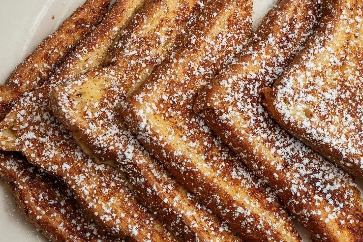 Close-up of golden-brown fried bananas sprinkled with powdered sugar.