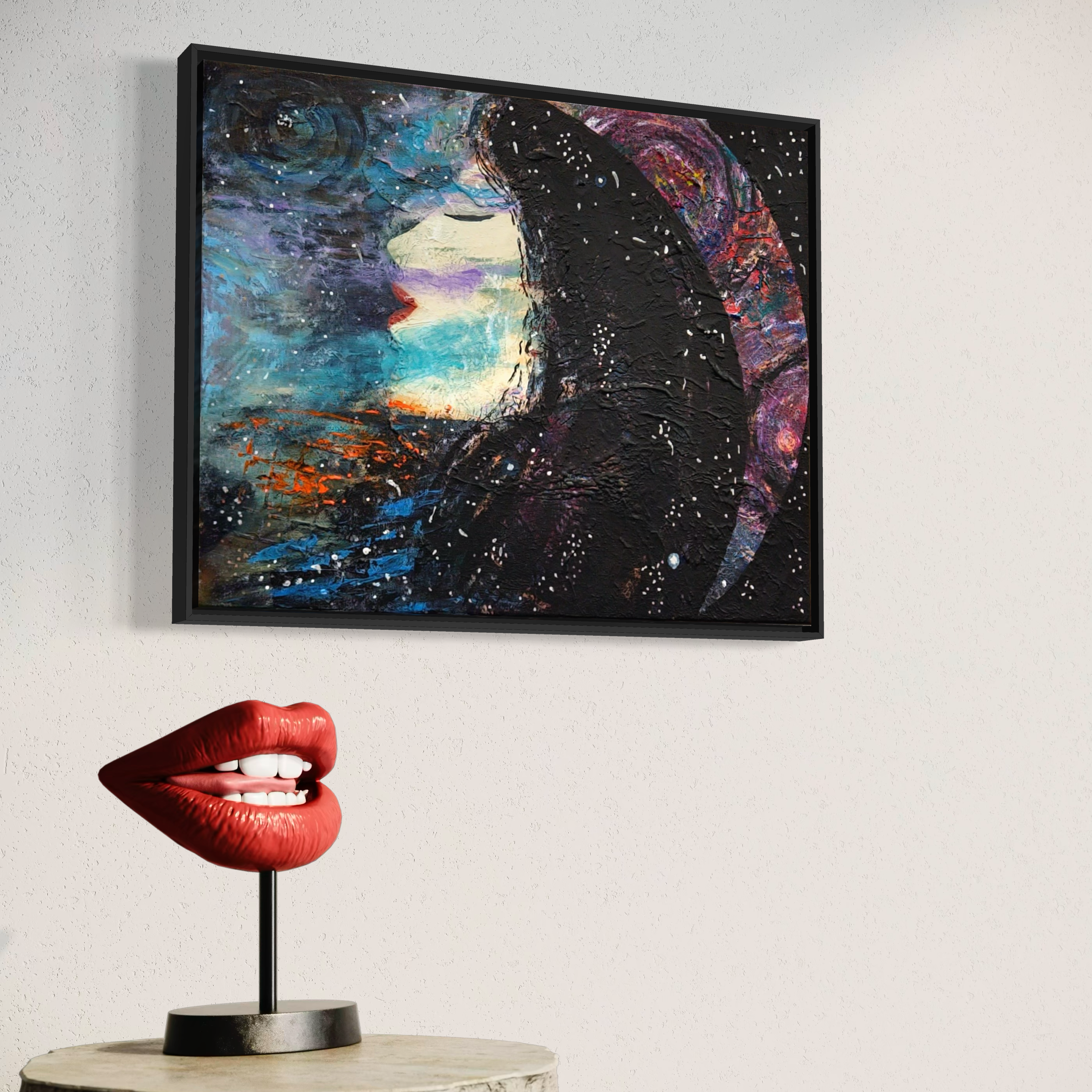 Decorative art on wall of a woman in profile with cosmic background, and a lipstick-shaped sculpture with lips on a stand on a table.