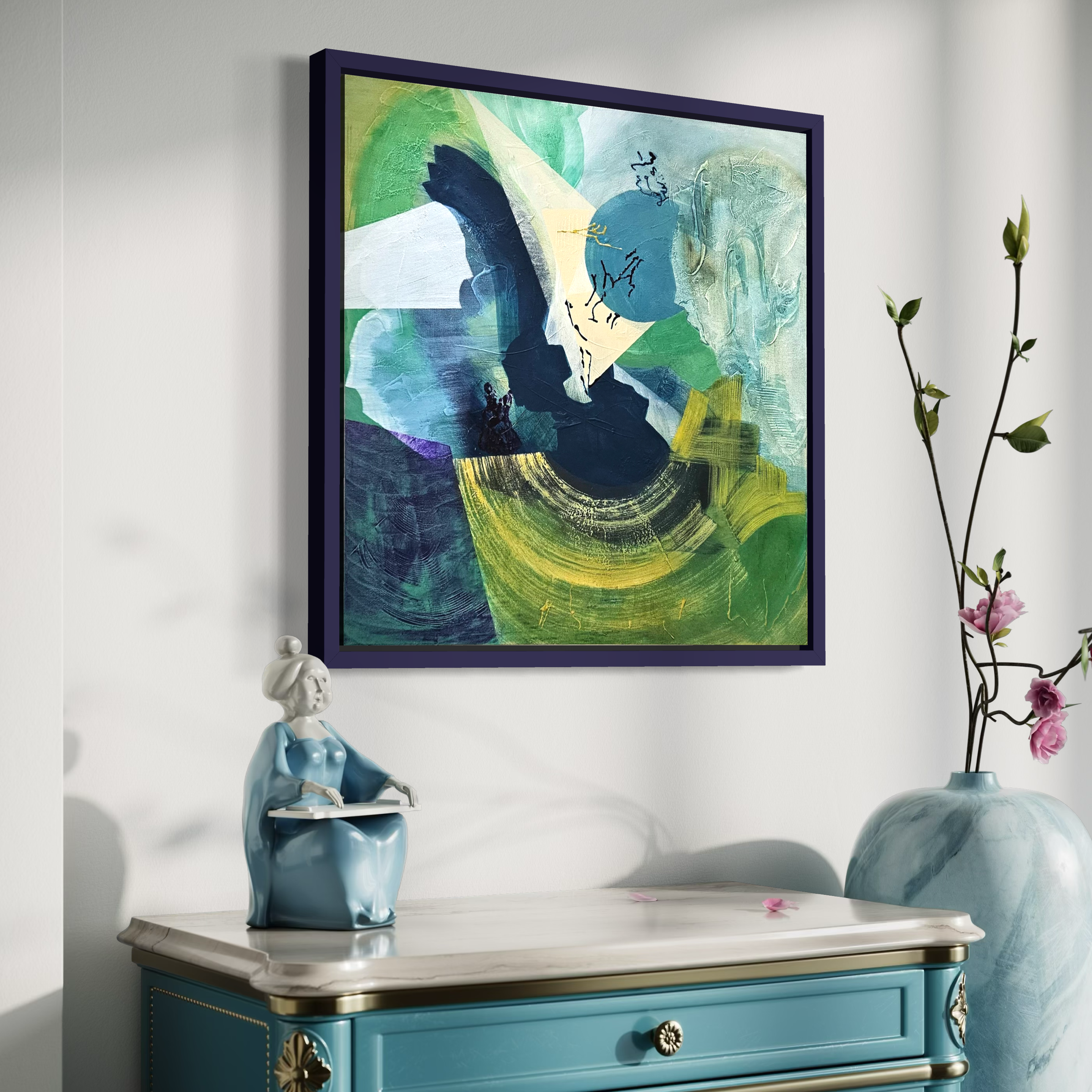 An abstract painting with shades of green, blue, white, and black hangs on a wall above a light blue dresser. A ceramic figurine of a girl in traditional dress sits on the dresser, and a tall vase with pink flowers is to the right.