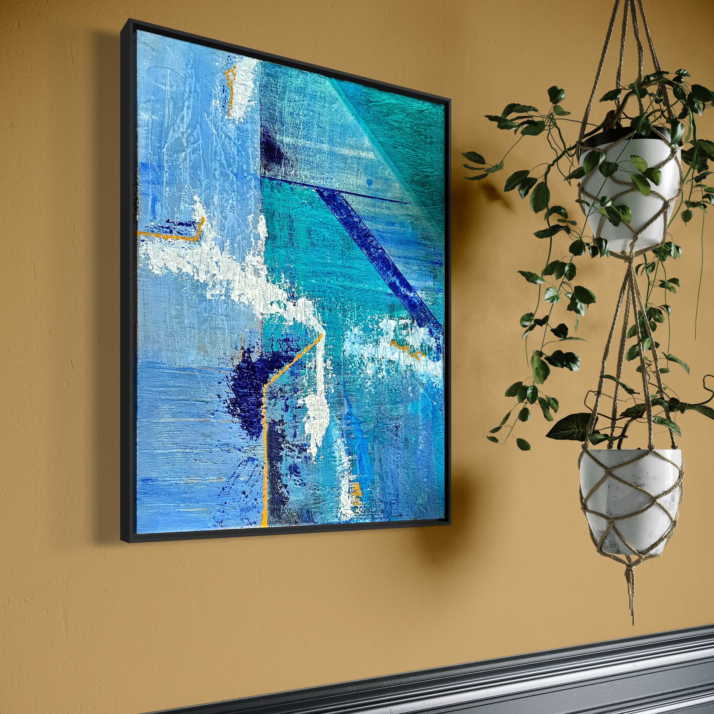 Blue abstract painting next to a hanging potted plant on a beige wall.