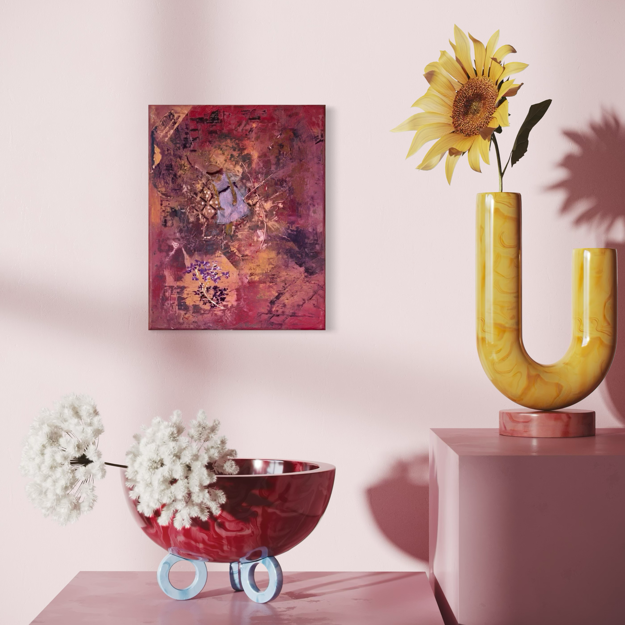 Decorative pink wall with abstract painting, yellow sunflower in a yellow marble-patterned vase on a pink pedestal, and a red glass bowl with white flowers with round glass feet.