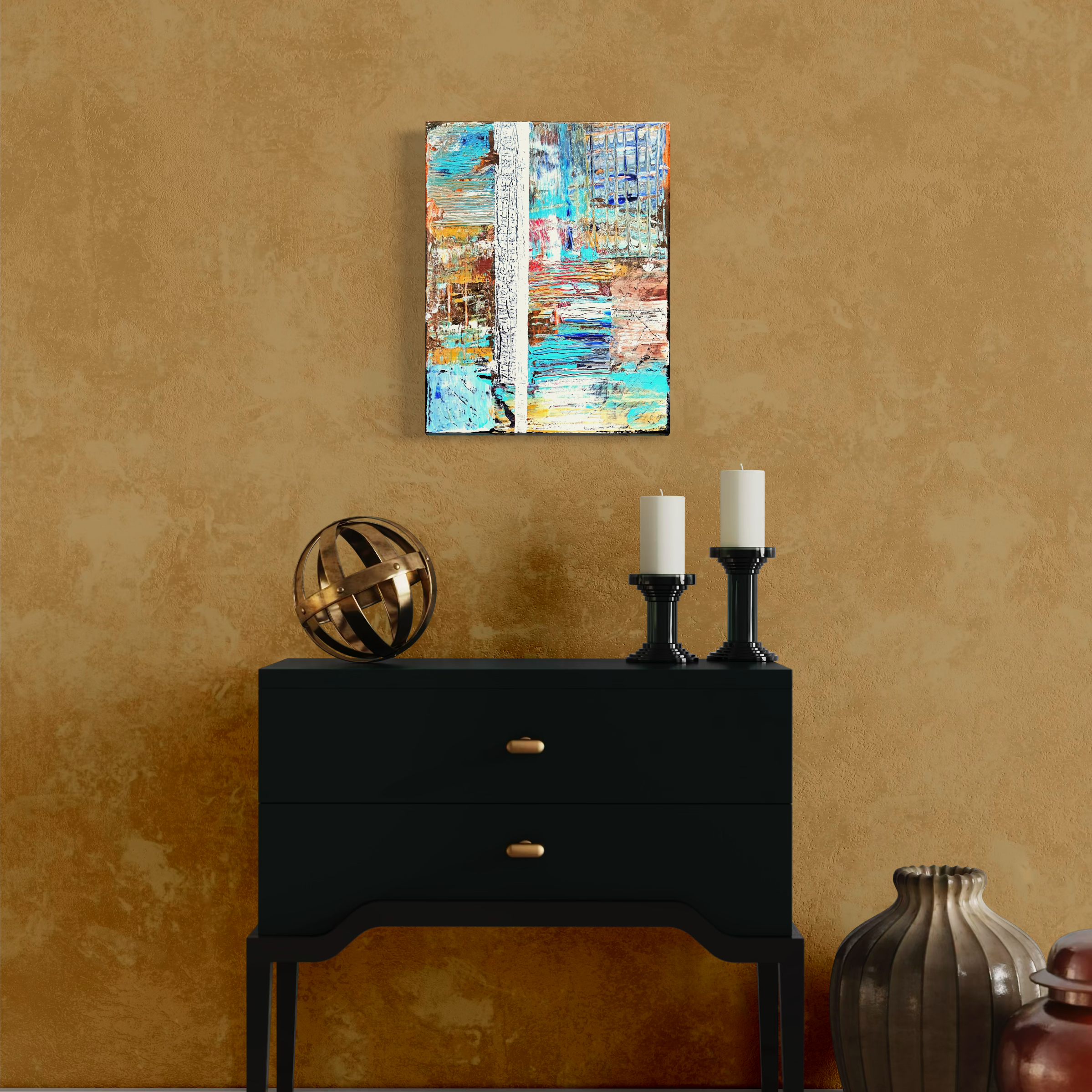 Decorative black console table with two white candles on black candlesticks and a metallic orb sculpture on a gold textured wall. Abstract colorful painting hangs above.