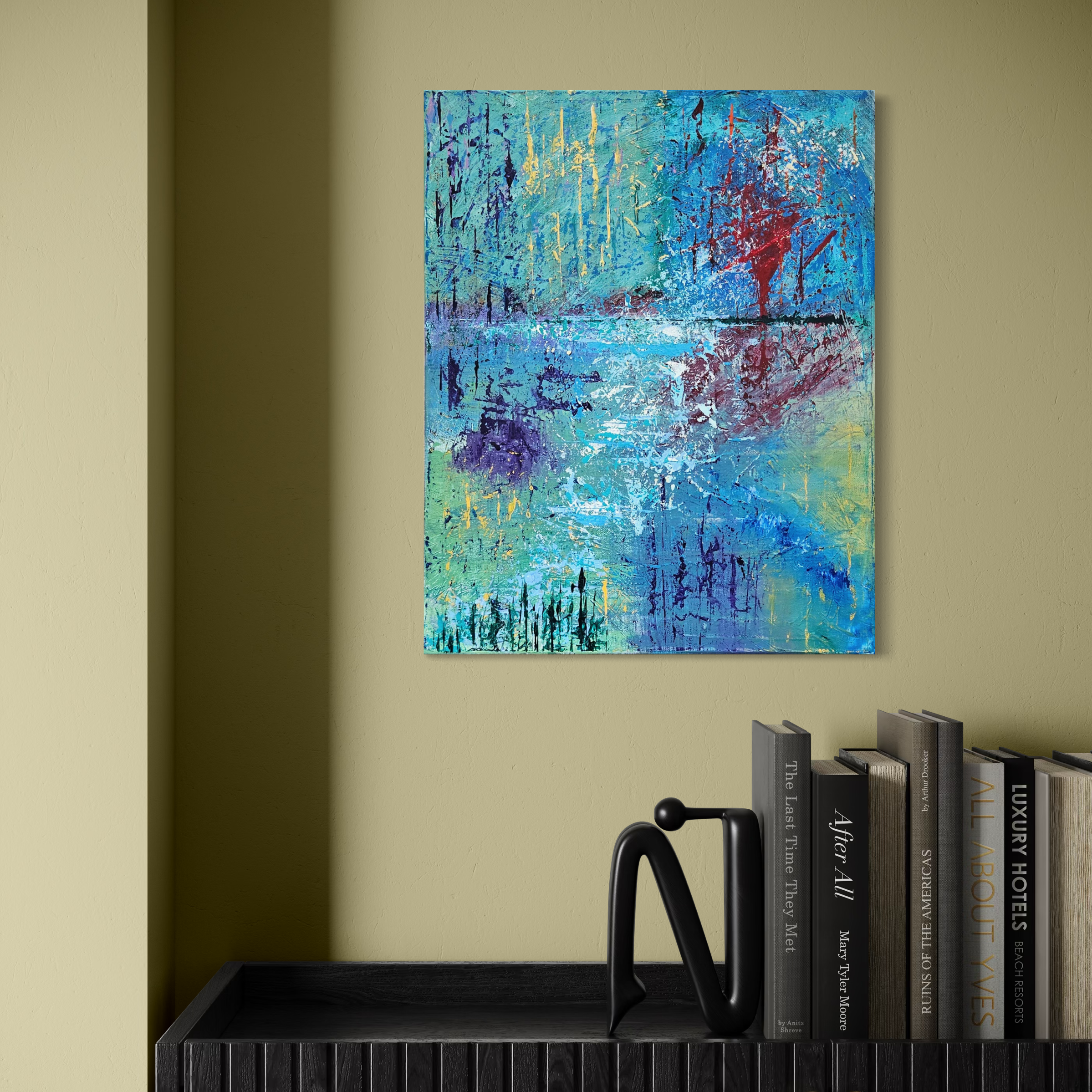 Abstract blue and red painting on a beige wall above a black shelf with books and a black decorative object.