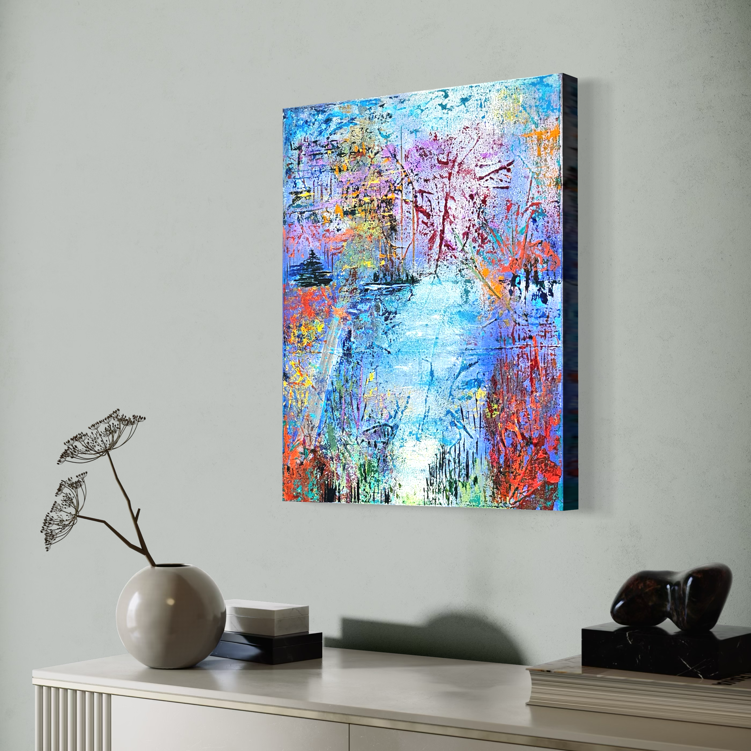 Abstract colorful painting of trees and a river on wall above a console table with decor items.