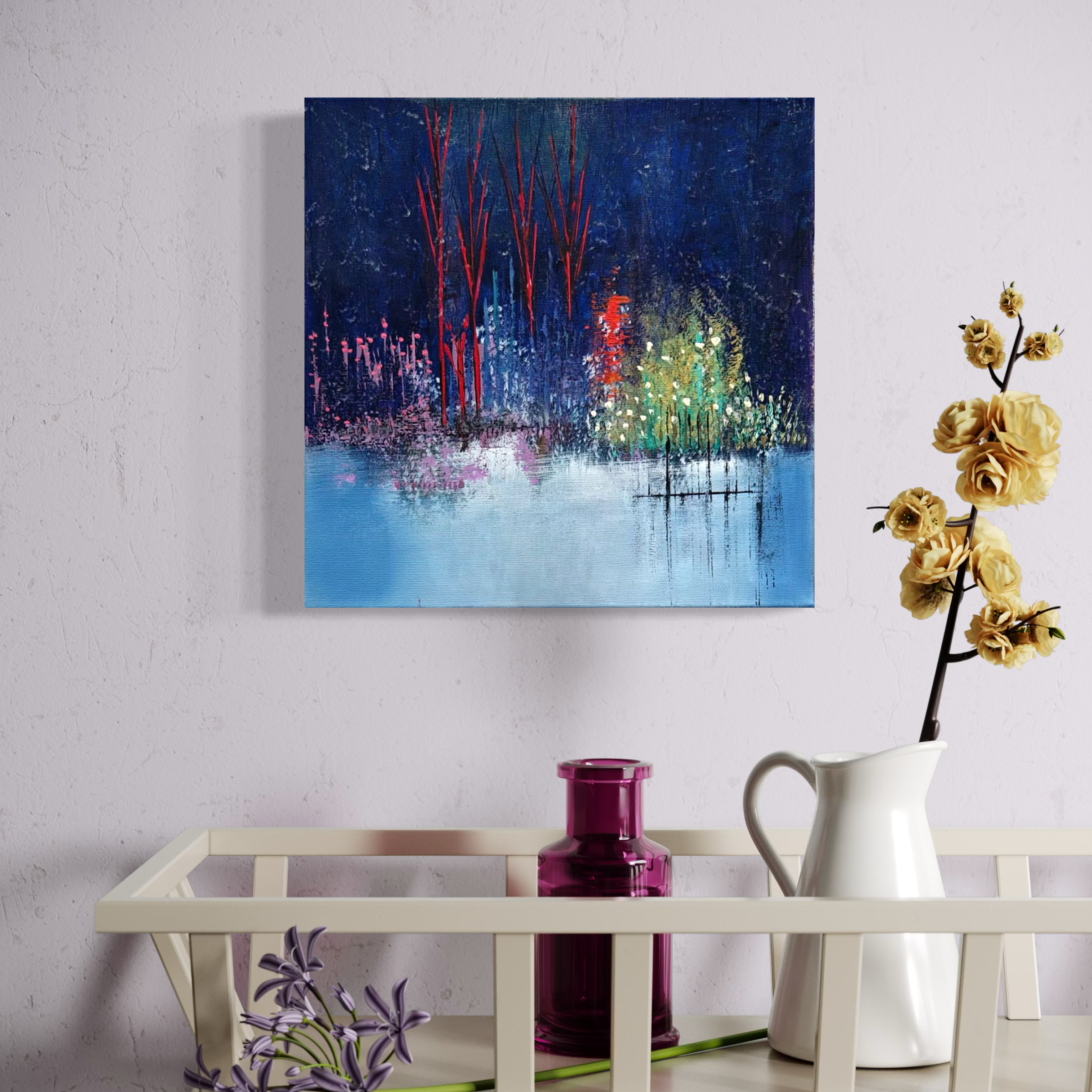 A colorful abstract landscape painting depicting trees and reflections on water, hung on a white wall near a table with a white pitcher holding a branch of yellow flowers and a purple vase, with a purple flower on the table.