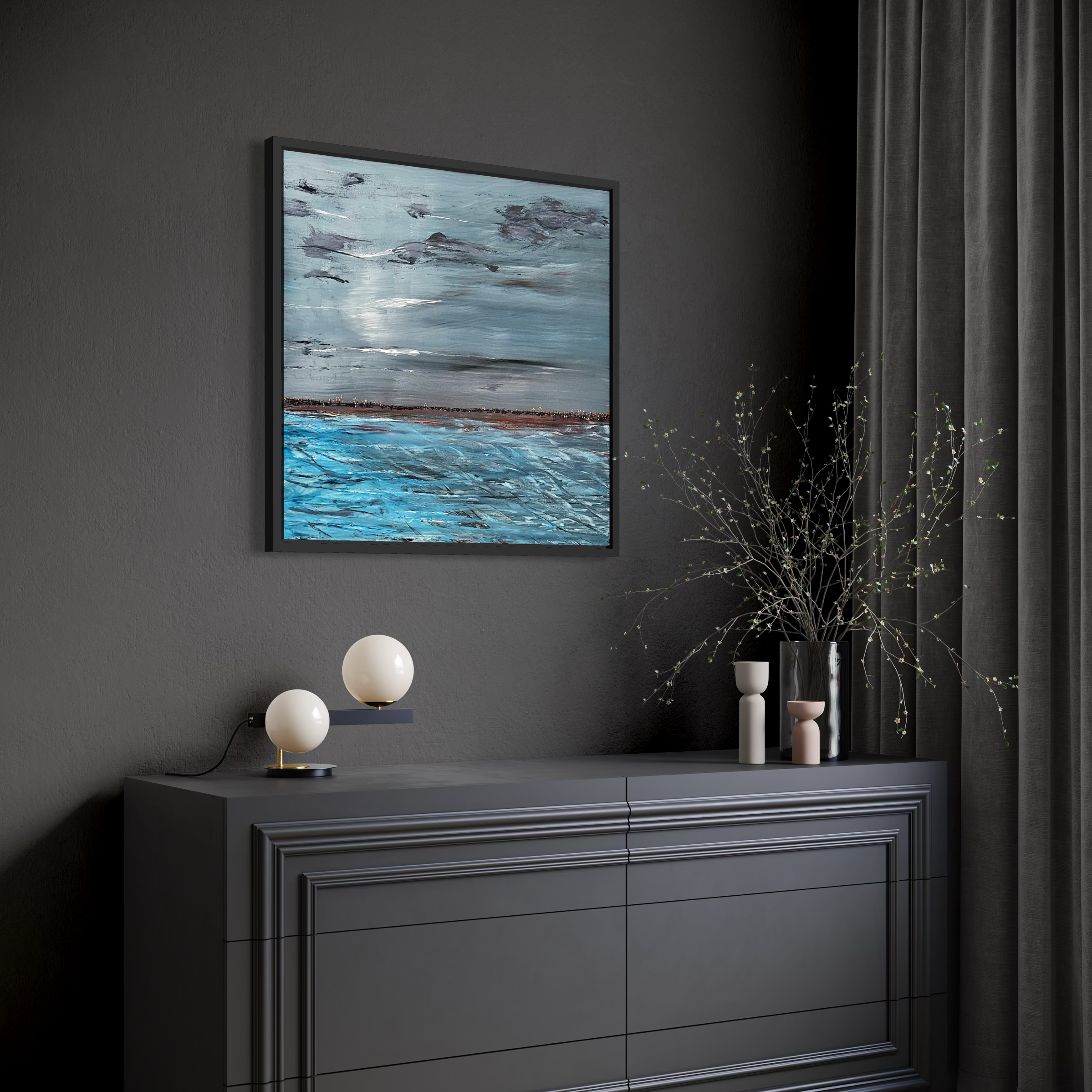 Dark gray sideboard with three drawers, decorated with two modern spherical lamps, a tall vase with branches, smaller vases, and a framed landscape painting of water and sky on a dark gray wall next to gray curtains.