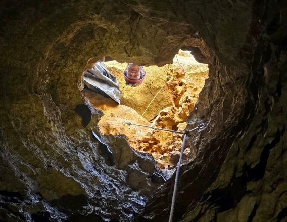 Looking up from inside a cave at a scientist at the entrance