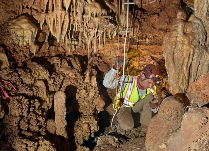 A Zara scientist in a safety vest surveying a cave