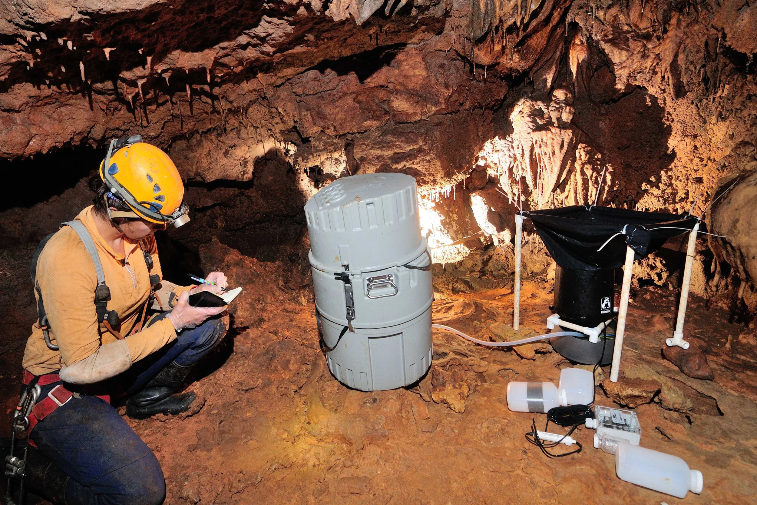 Zara scientist recording data beside water sampling equipment in a cave during a groundwater tracing study