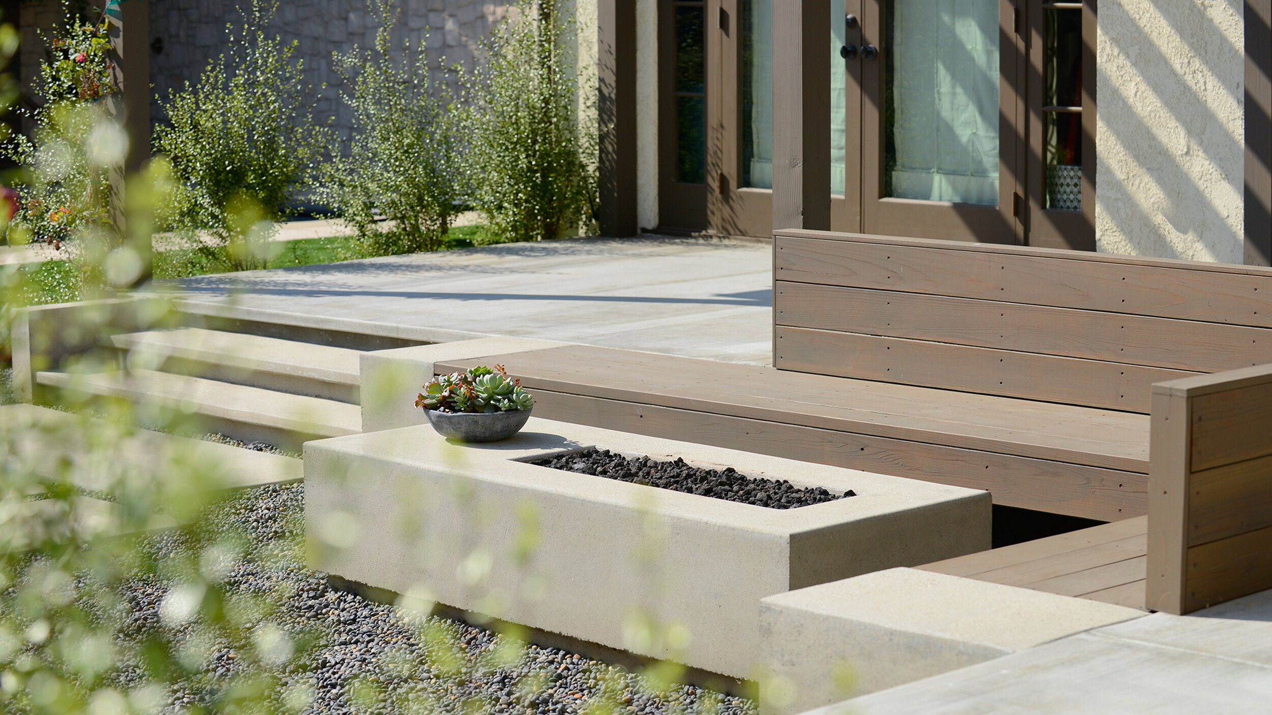 Spanish modern back yard landscape.  Natural color sand finish concrete built in couches create a sitting area around the asymmetrical sand finish firepit.